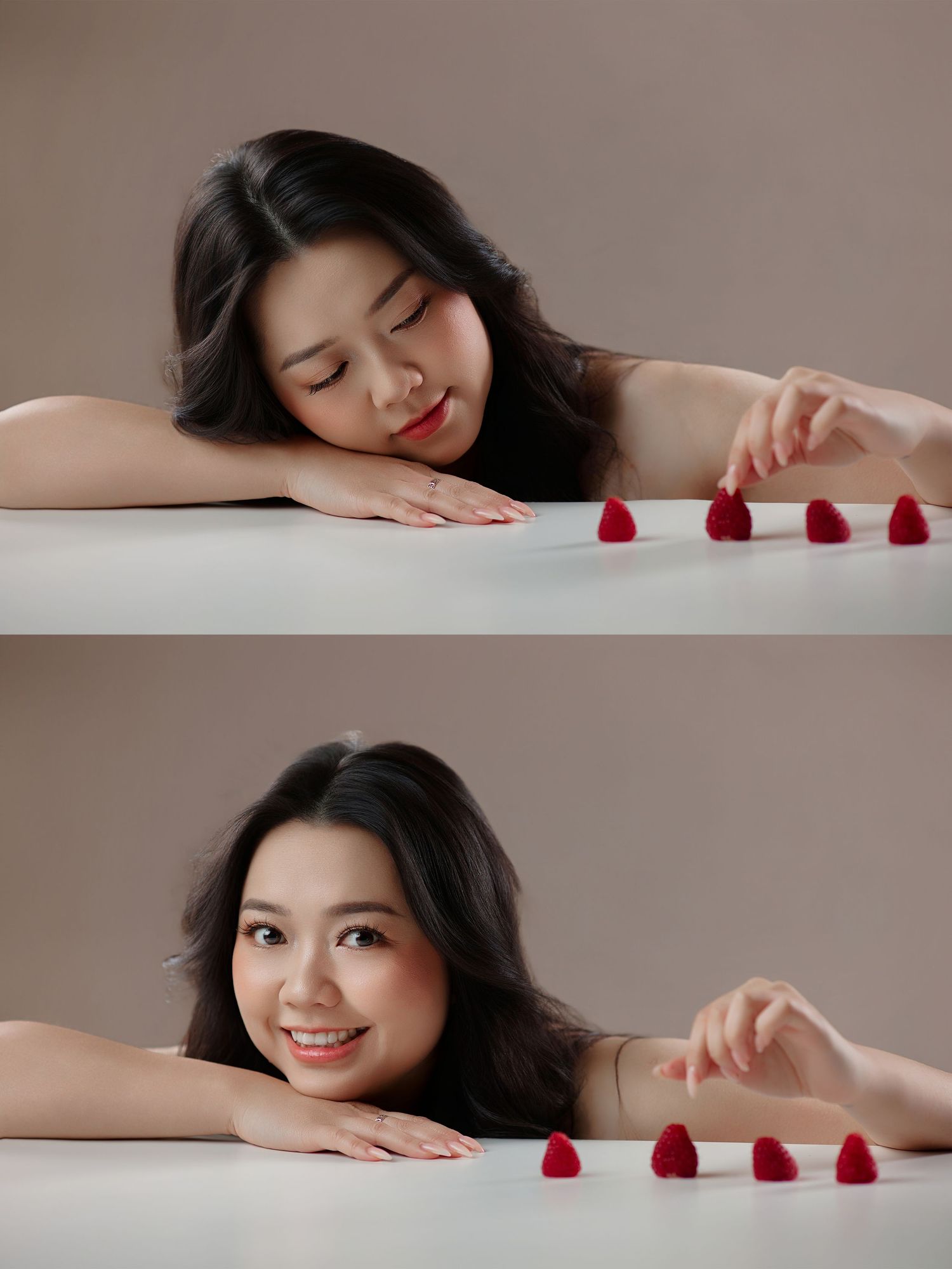 A young Asian woman rests her chin on a white table, smiling softly while arranging small red raspberry candies.