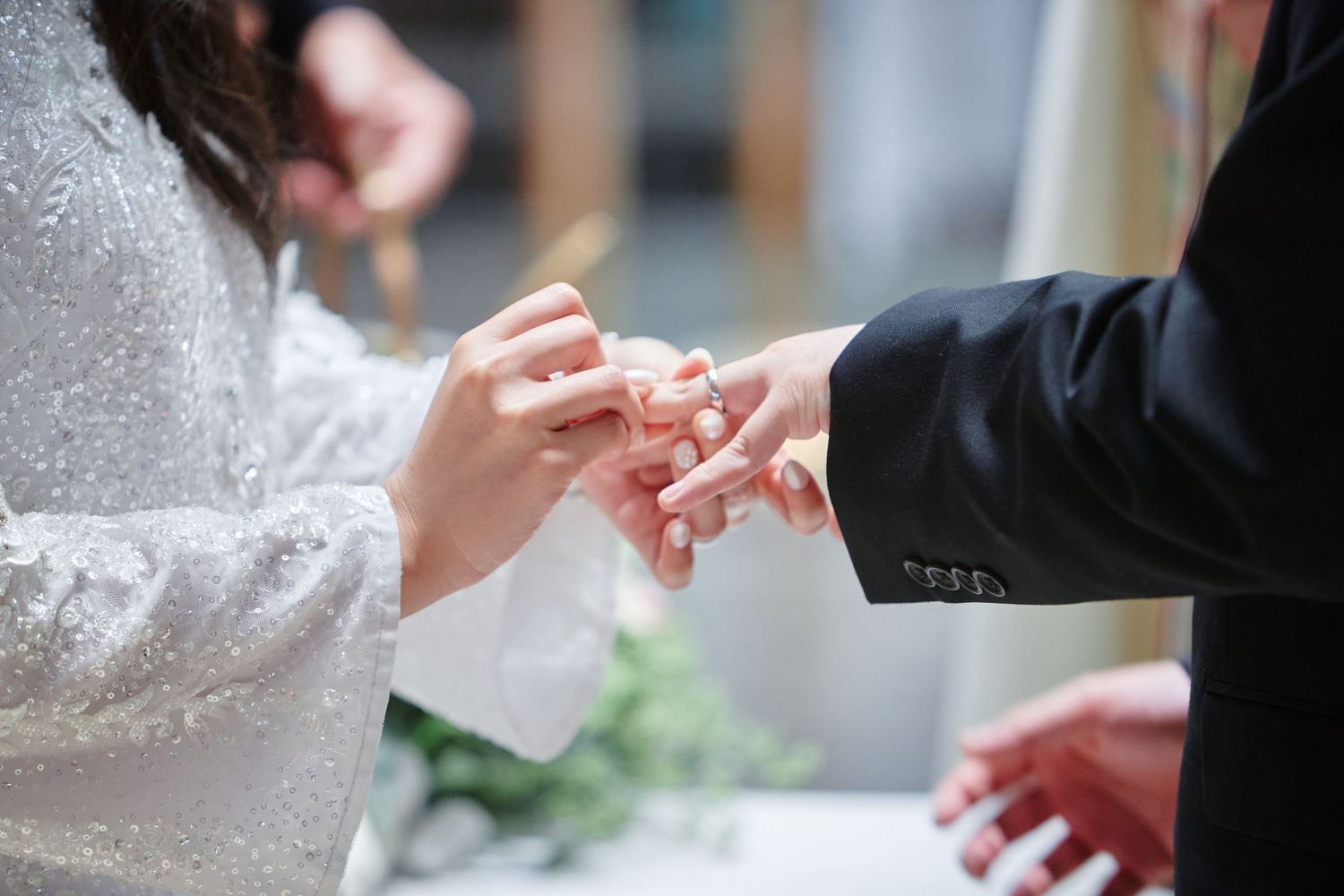 Bride placing a wedding ring on groom's finger during a wedding ceremony, symbolizing love and commitment.