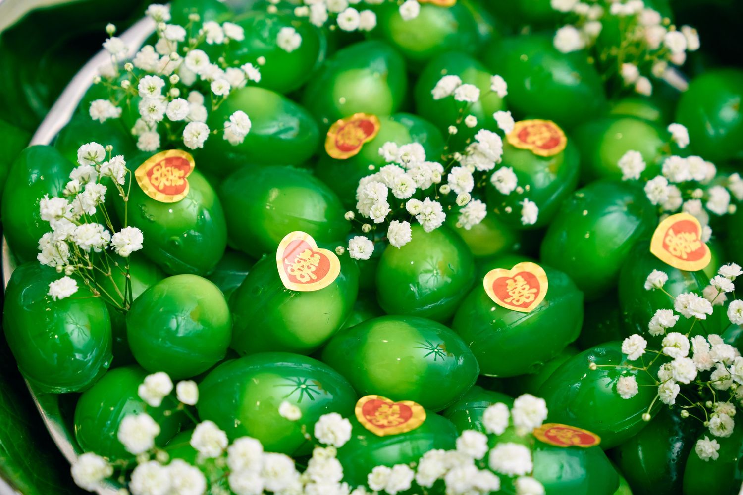 Green limes decorated with small white baby's breath flowers and orange sticker labels arranged in a decorative display.
