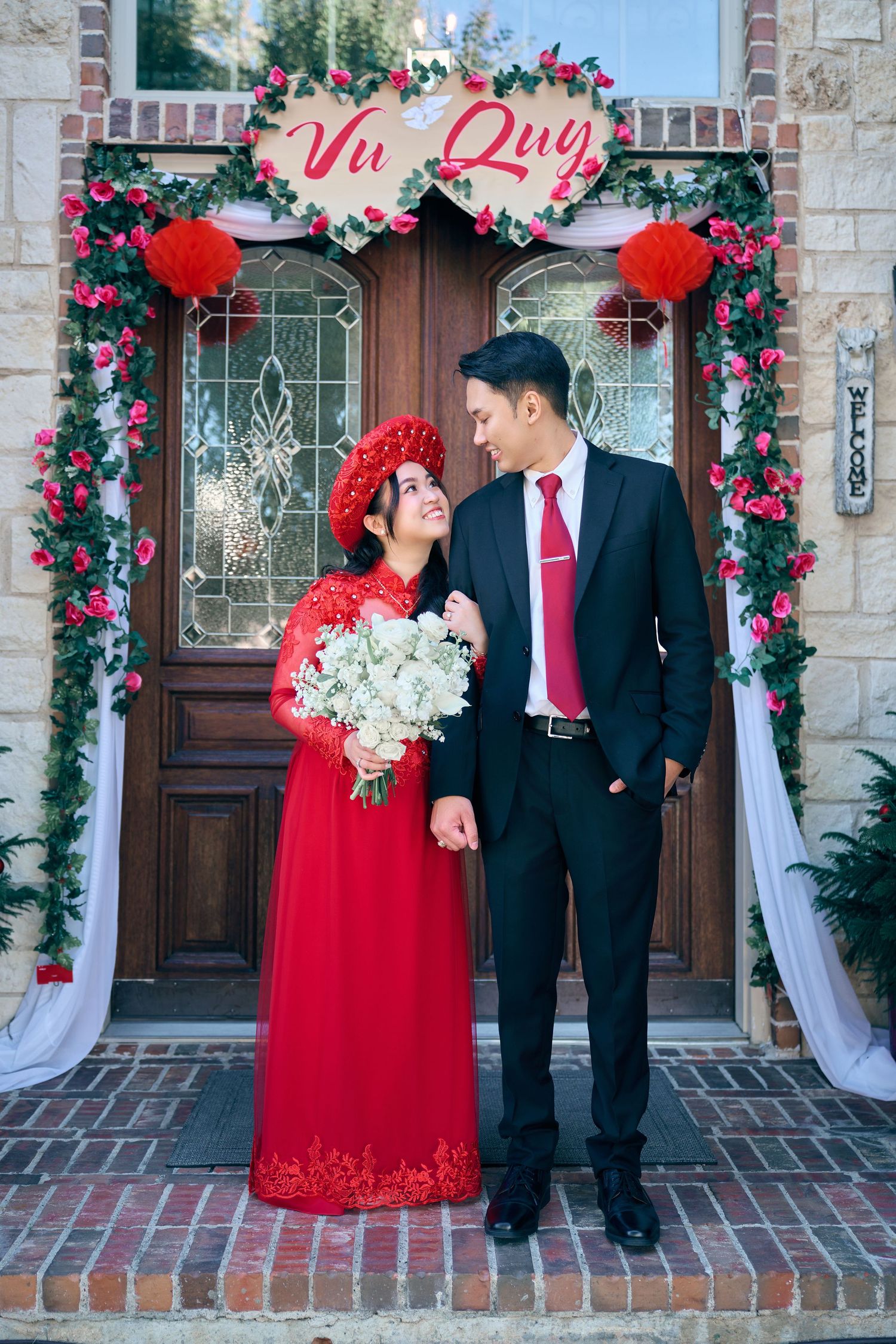 Vietnamese couple in traditional ao dai attire posing before a decorated Vu Quy wedding entrance.