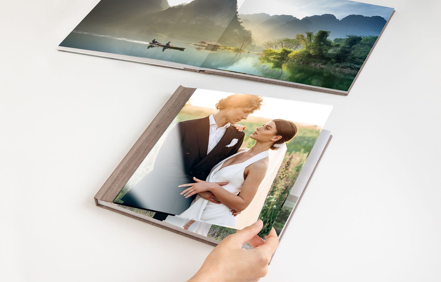 Two photo books displayed on a white surface, one open showing a wedding couple portrait on the cover.