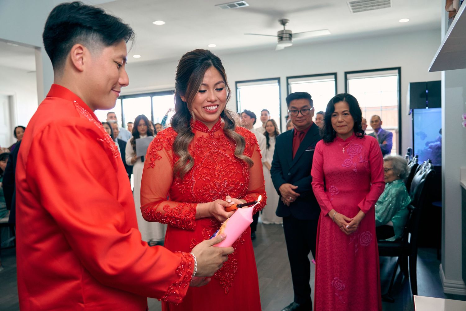 Vietnamese couple in red ao dai exchanging gifts during traditional wedding ceremony with guests watching.