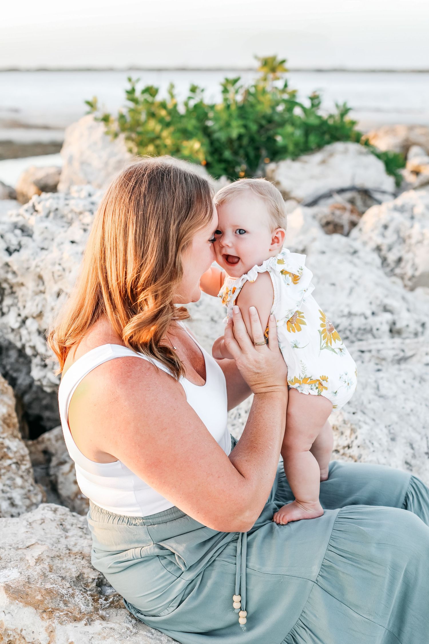 A tender moment shared between parent and child sitting on a sandy beach during a sunset photo session.