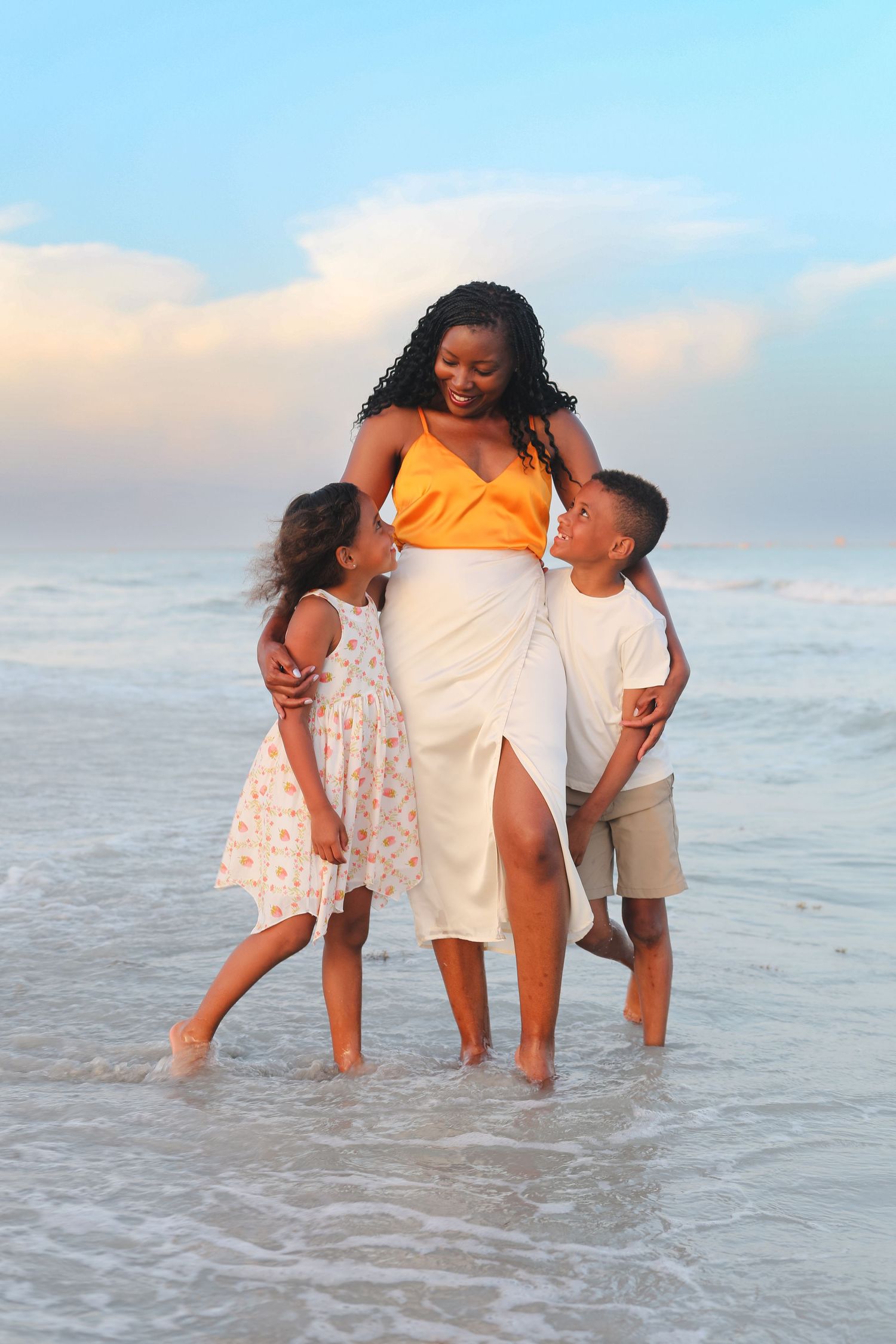 Family members playing and splashing in ocean waves during sunset photoshoot.