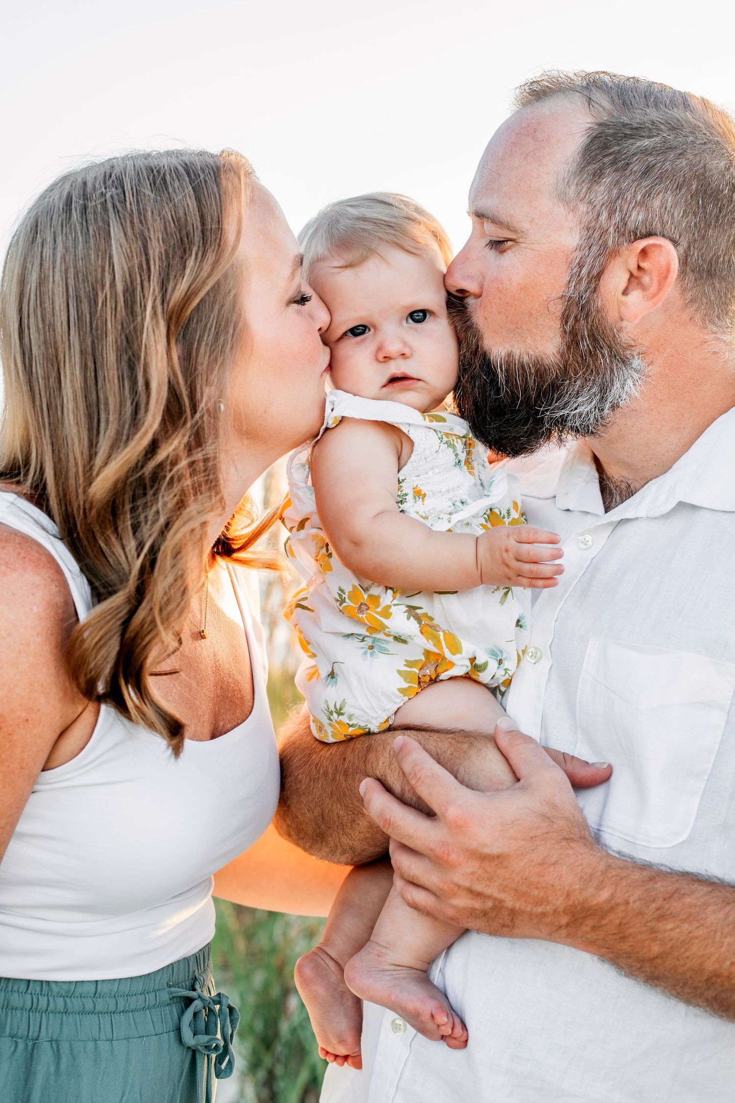 A sweet series of family moments captured outdoors with gentle kisses and tender embraces in natural lighting.