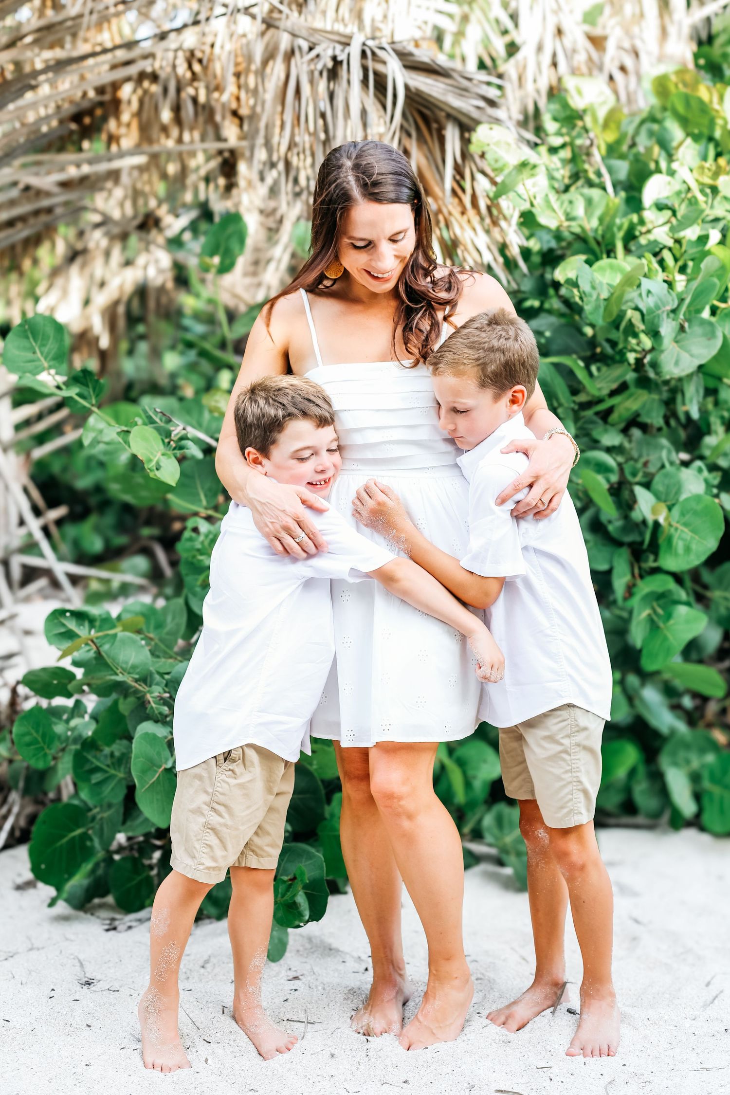 Family photo session on beach with coordinated white outfits and natural backdrop.