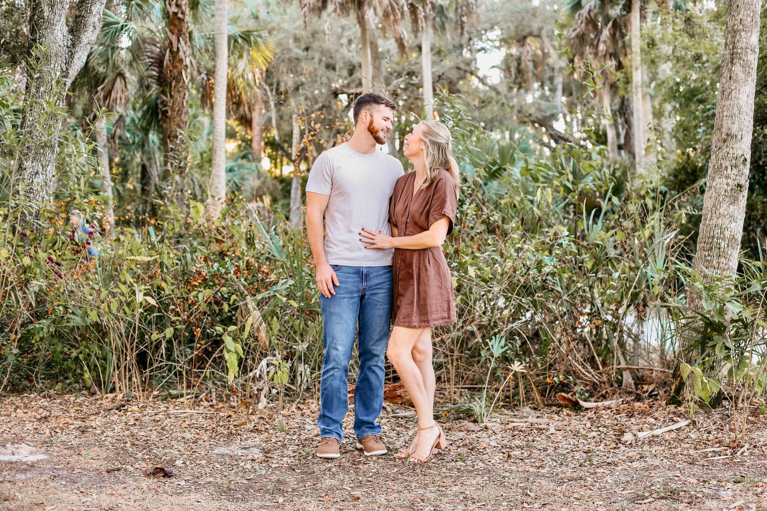 A couple shares romantic moments together in a wooded outdoor setting during a photo session.