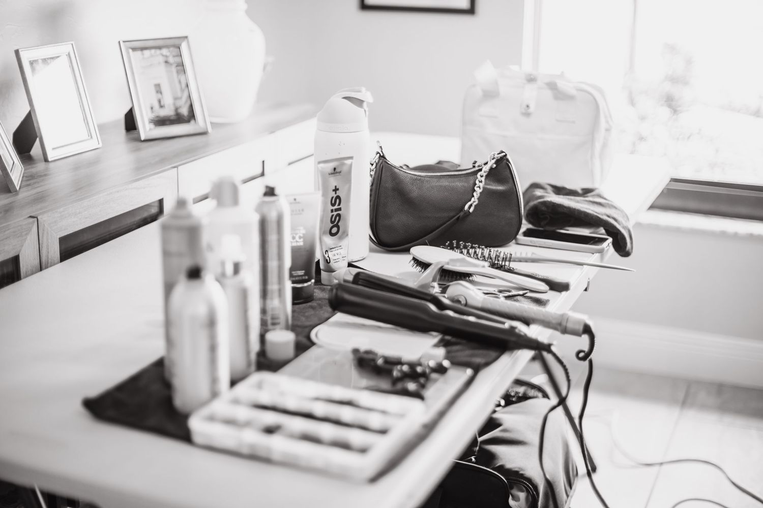 Black and white photo of hair salon tools, styling products, and accessories arranged on a professional styling station.