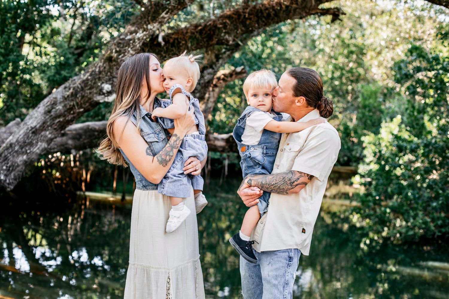 A family enjoys tender moments together during an outdoor photo session in a sunlit garden setting.