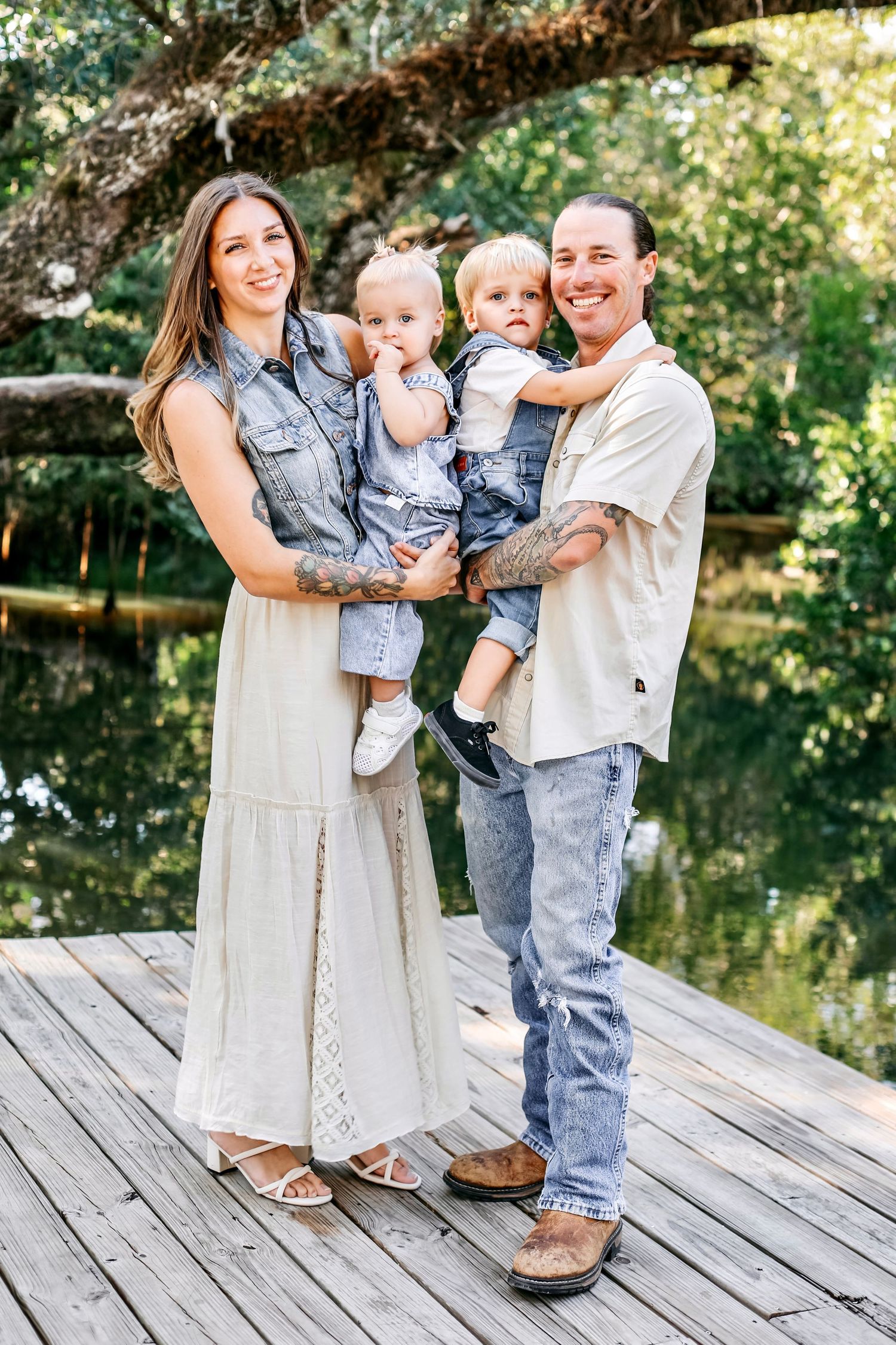 Family portrait session on wooden deck by pond showing sweet candid moments in coordinated casual outfits.