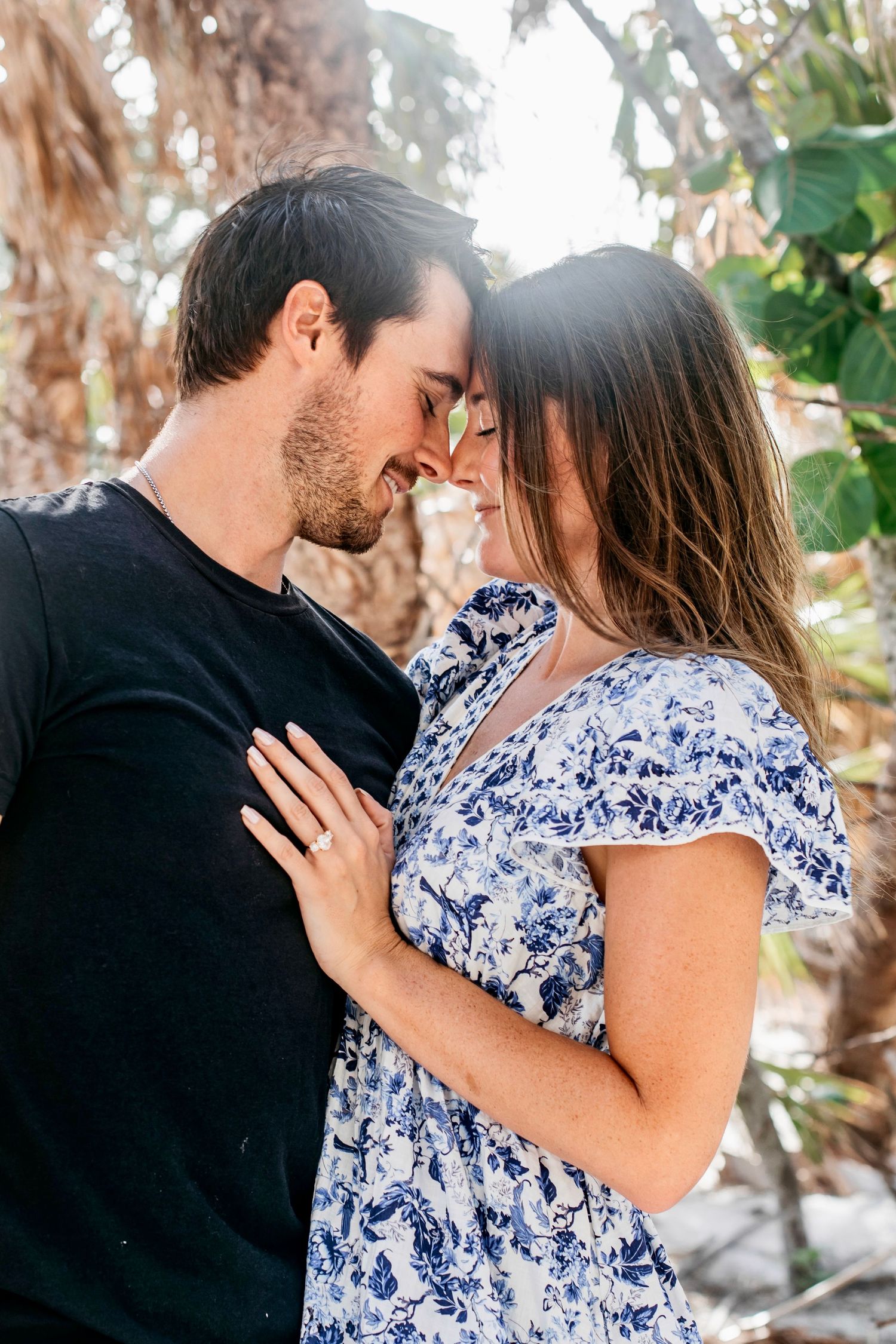 Intimate couple's photoshoot among tropical foliage on beach.