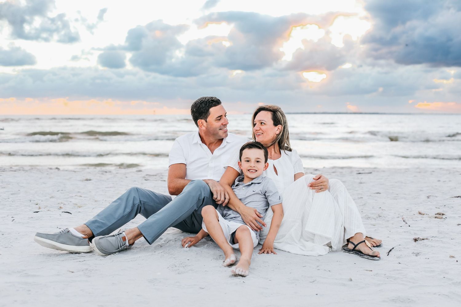 Romantic couple laughing and playing together on a white sandy beach at sunset.