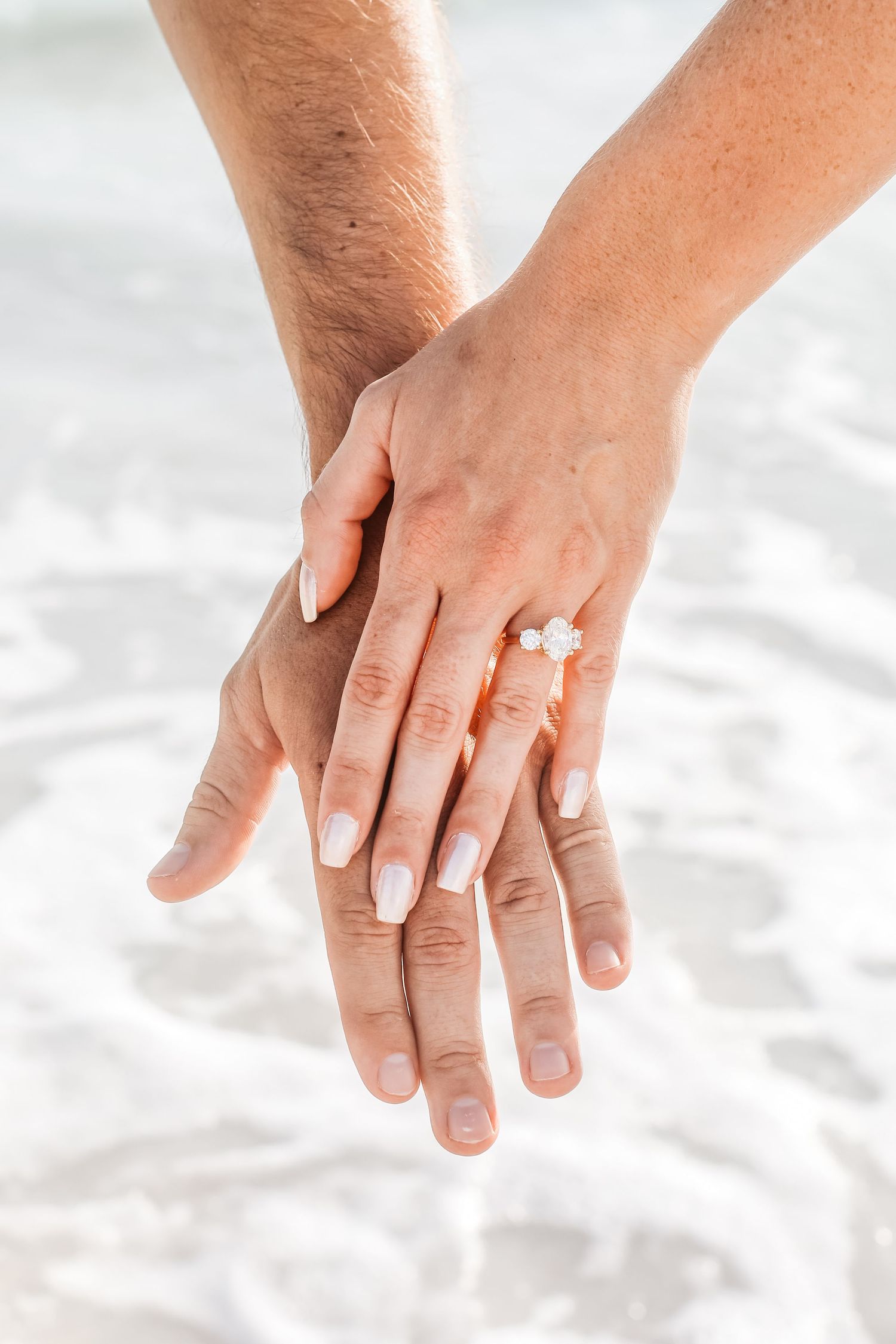 Close-up shot of hands touching against white sandy beach background.