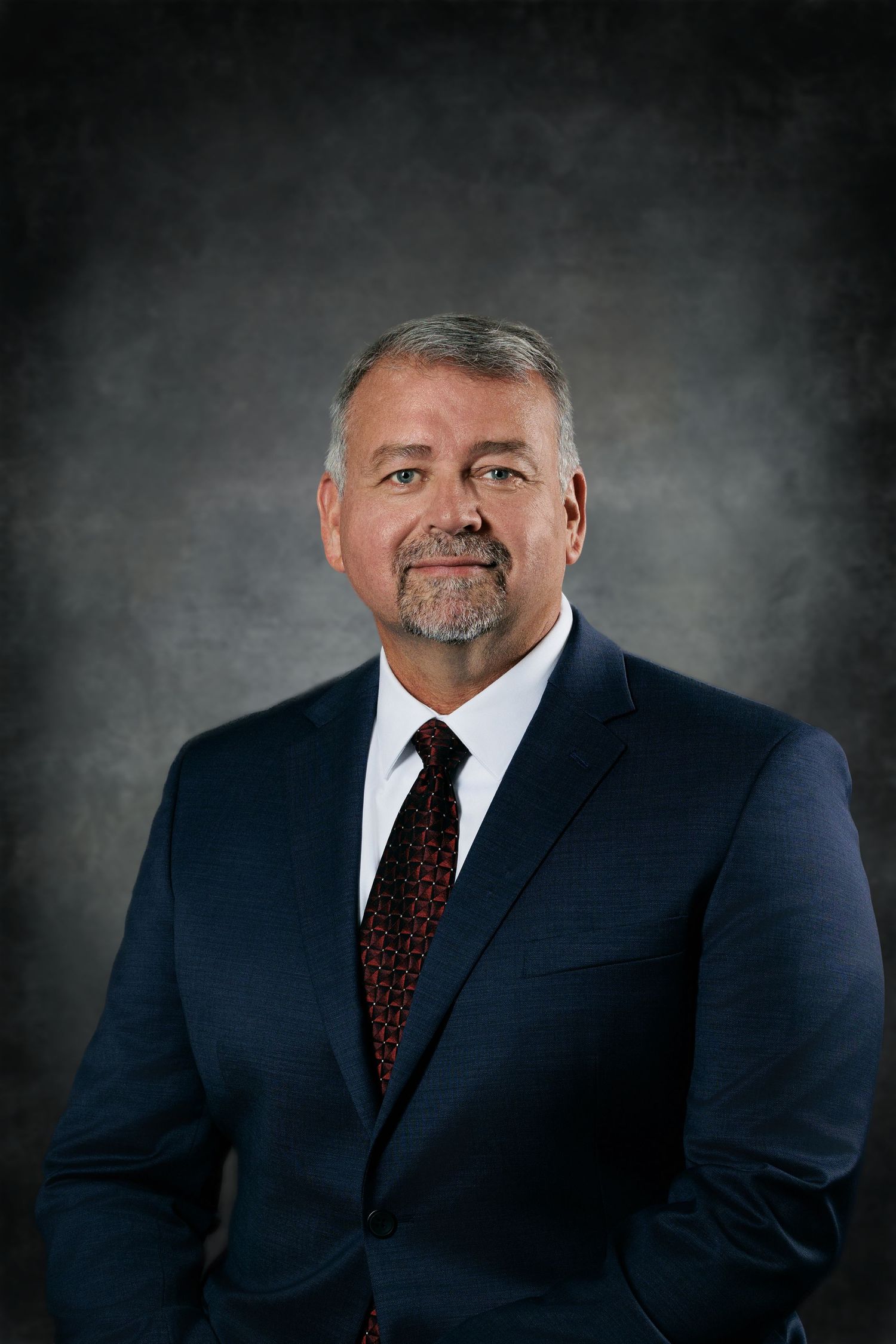 Professional portrait series showing a person in a navy suit and burgundy tie against a dark gray studio backdrop.