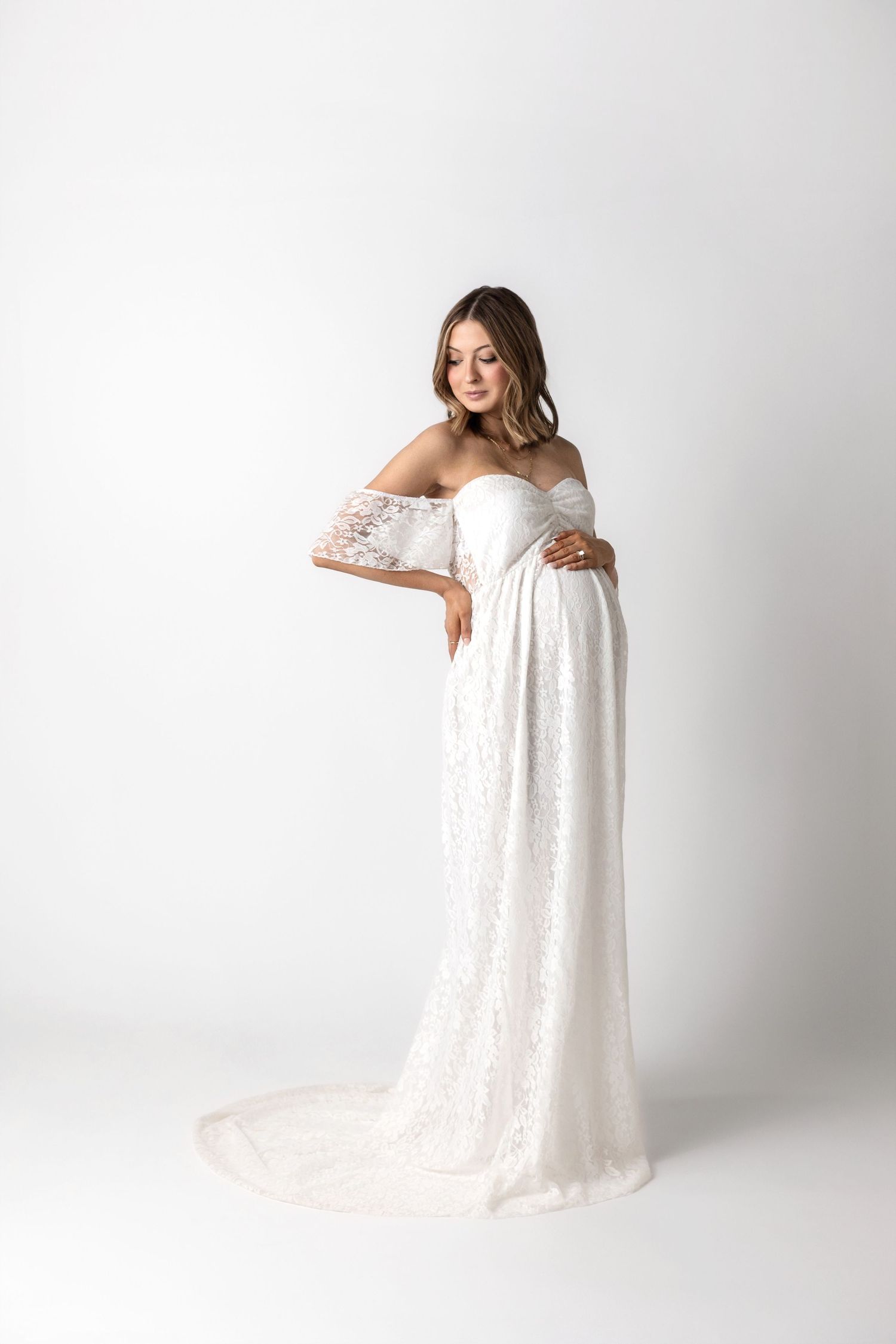 A white lace maternity gown photographed in four elegant poses against a light studio background.