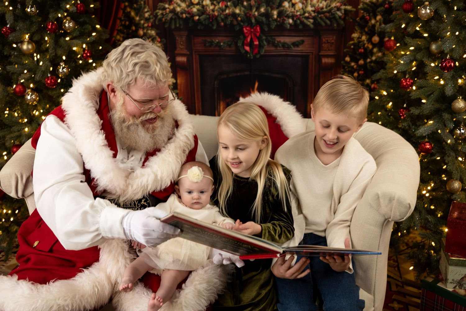 Santa Claus reads a Christmas book with three children by a decorated tree and fireplace.