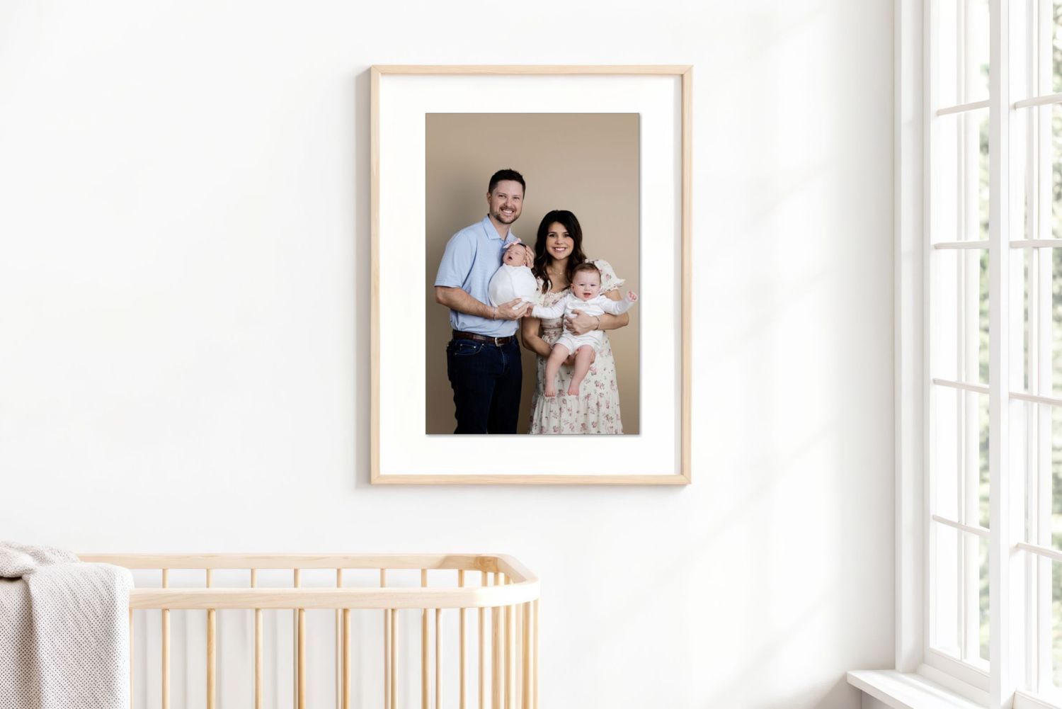 Nursery wall features luxury framed family portrait above wooden crib.