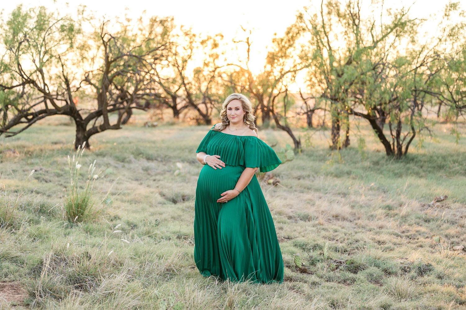 A person in a flowing emerald green dress twirls gracefully in a sun-dappled meadow at golden hour.