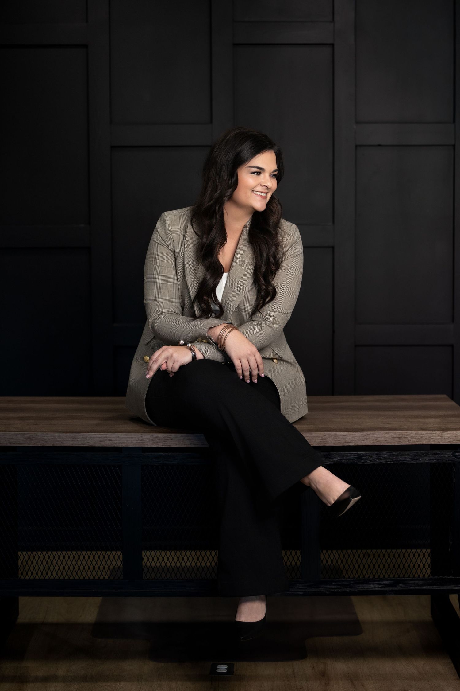 Professional portrait session against dark geometric wall featuring casual business attire and relaxed poses.