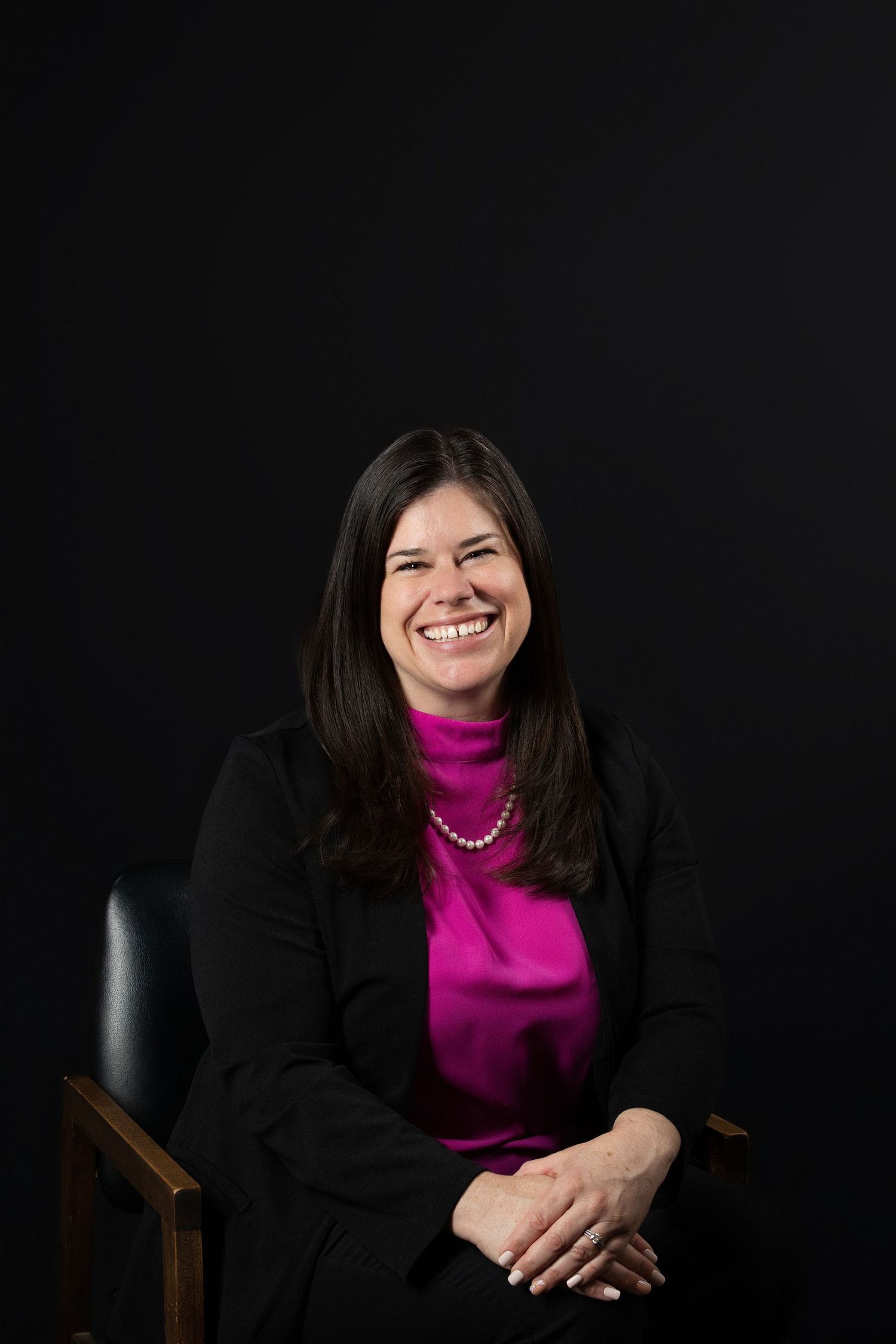 Professional portrait series against dark background showing person in black blazer and magenta turtleneck with warm expressions.