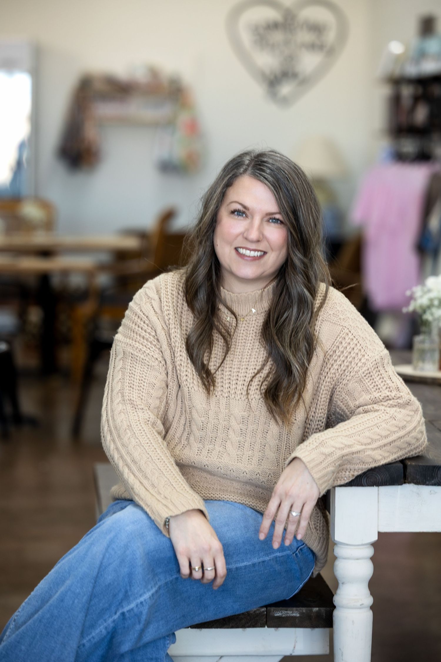 Casual portrait series showing someone in a cream cable knit sweater and jeans relaxing on white furniture.