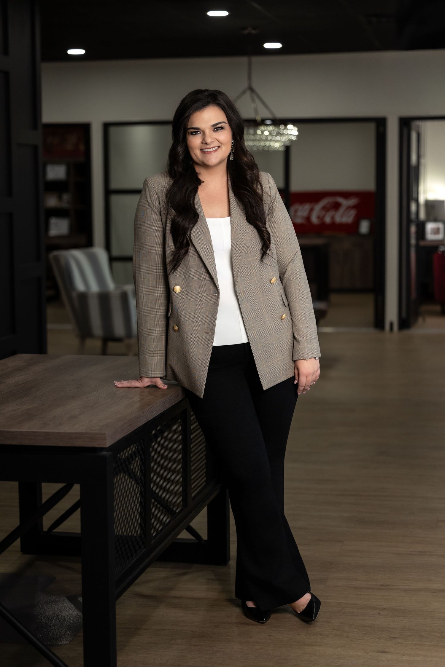 Professional business attire featuring a beige blazer and black pants in an indoor office setting with modern decor.