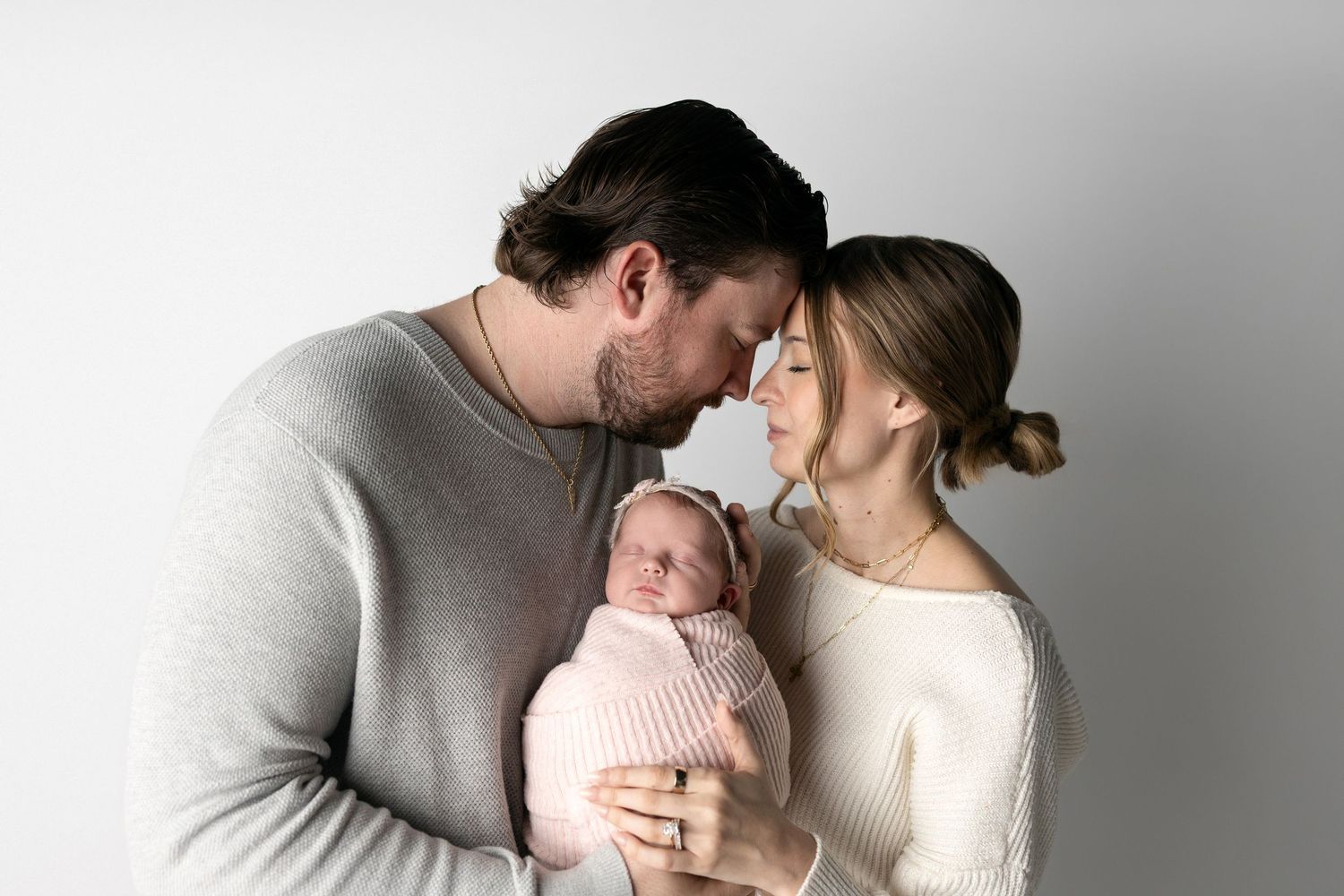 A tender family moment captured in a series of black and white photographs showing parents with their newborn baby.