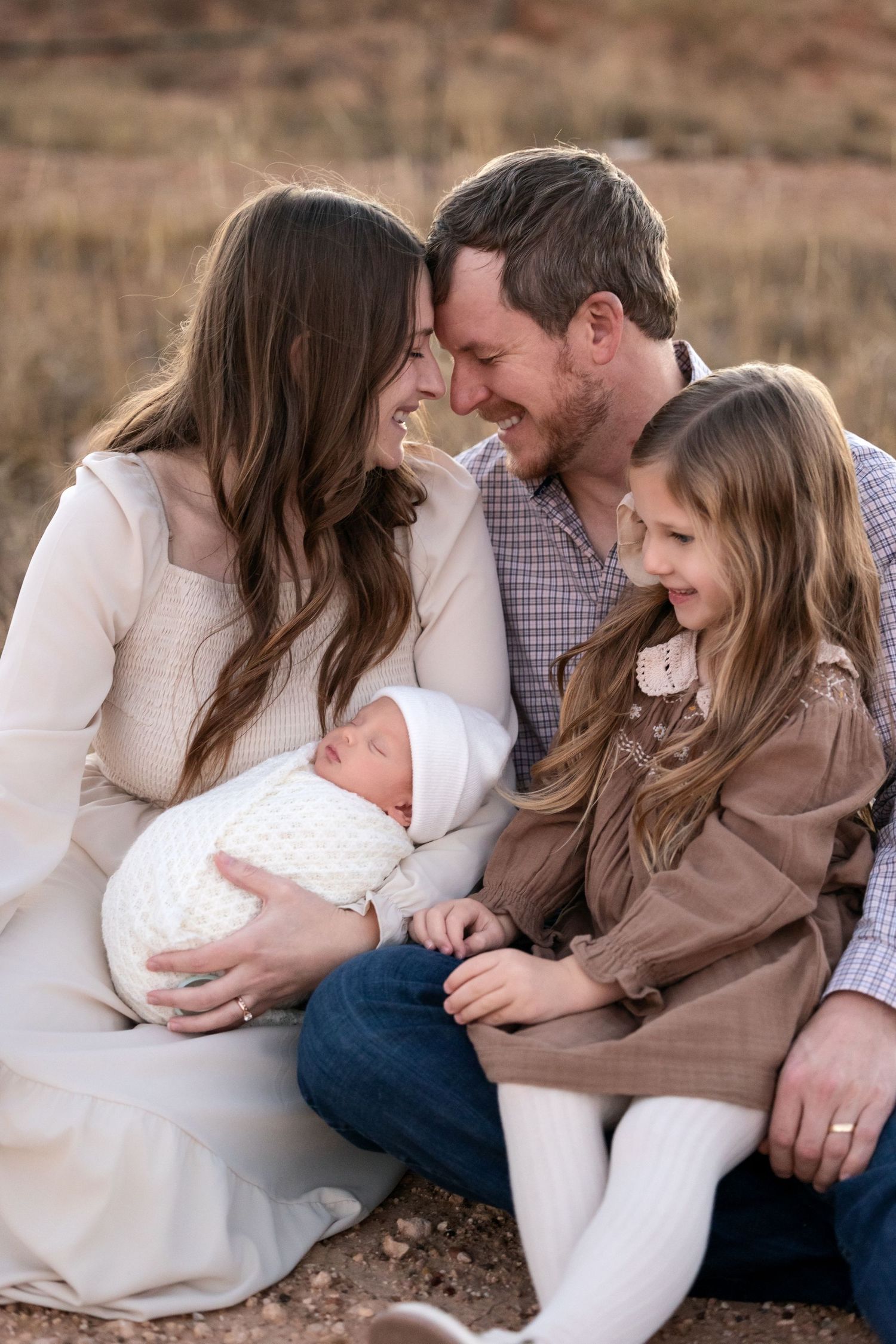 A family shares tender moments together while sitting outdoors against a desert landscape backdrop.