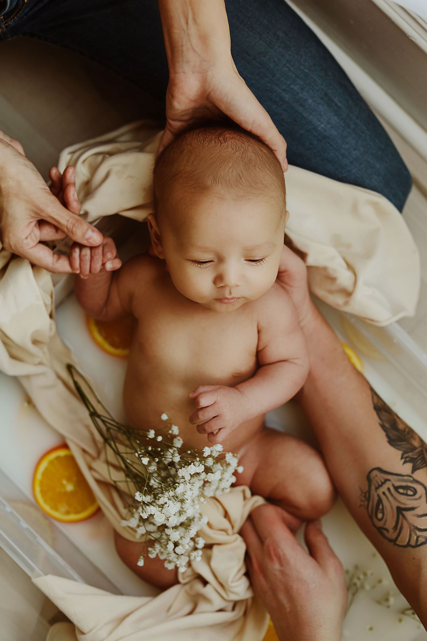 A peaceful bathing scene with citrus slices and baby's breath flowers surrounding an infant.
