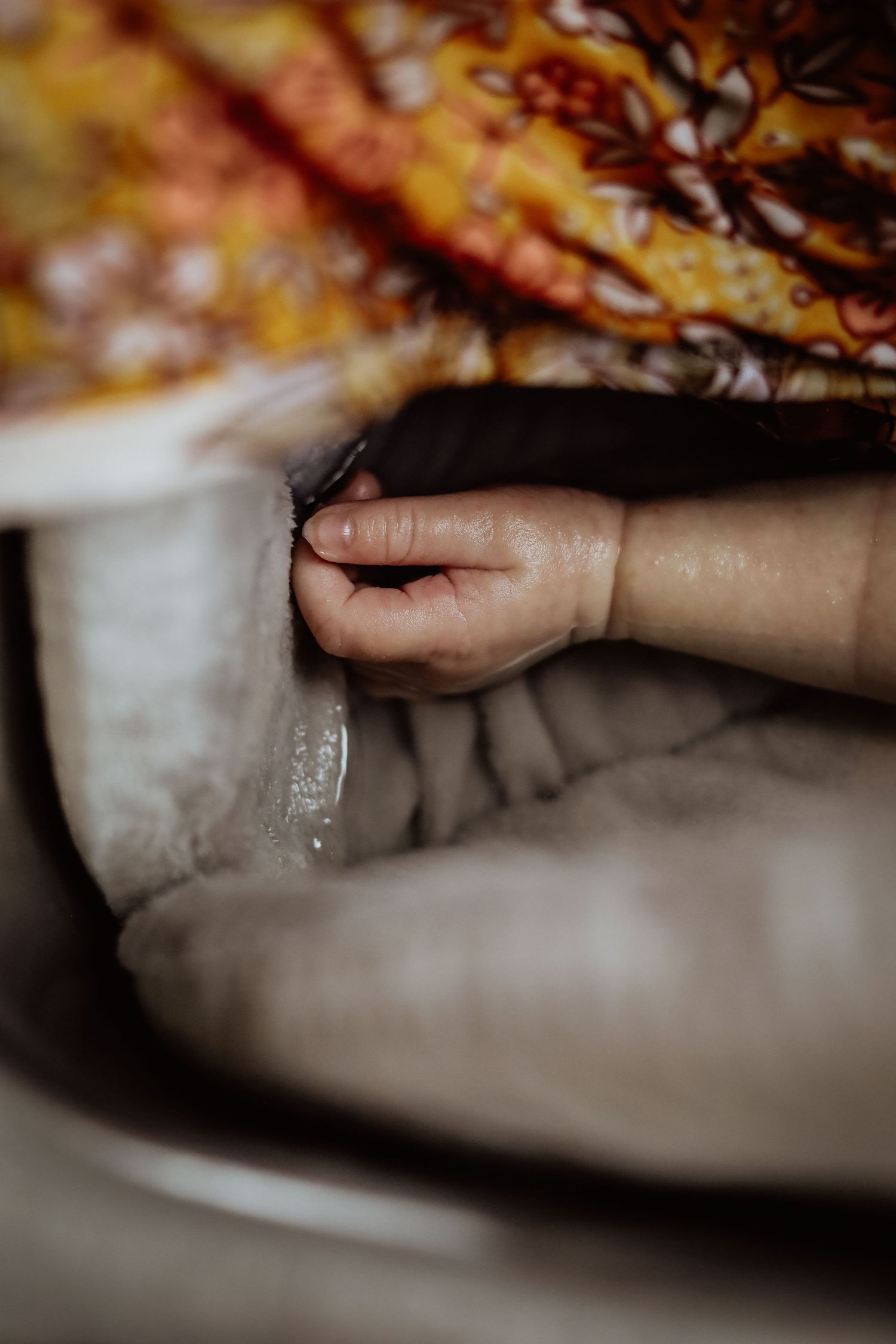 Close-up shot of a tiny hand grasping fabric in moody lighting.
