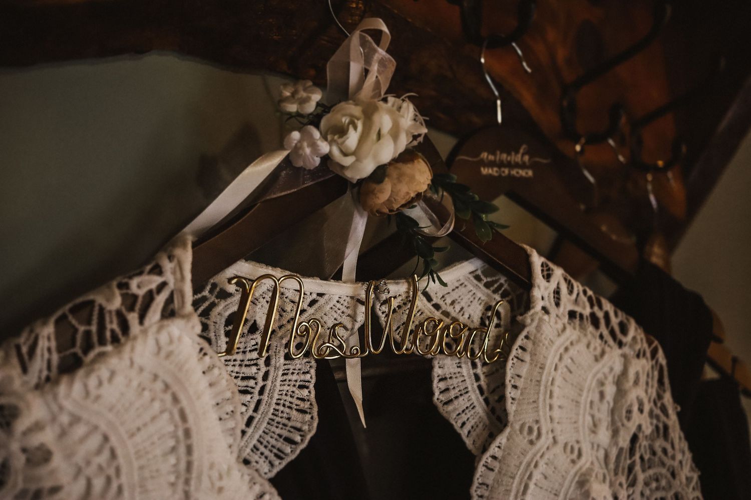 Detailed shot of intricate lace wedding dress hanging on vintage hanger.