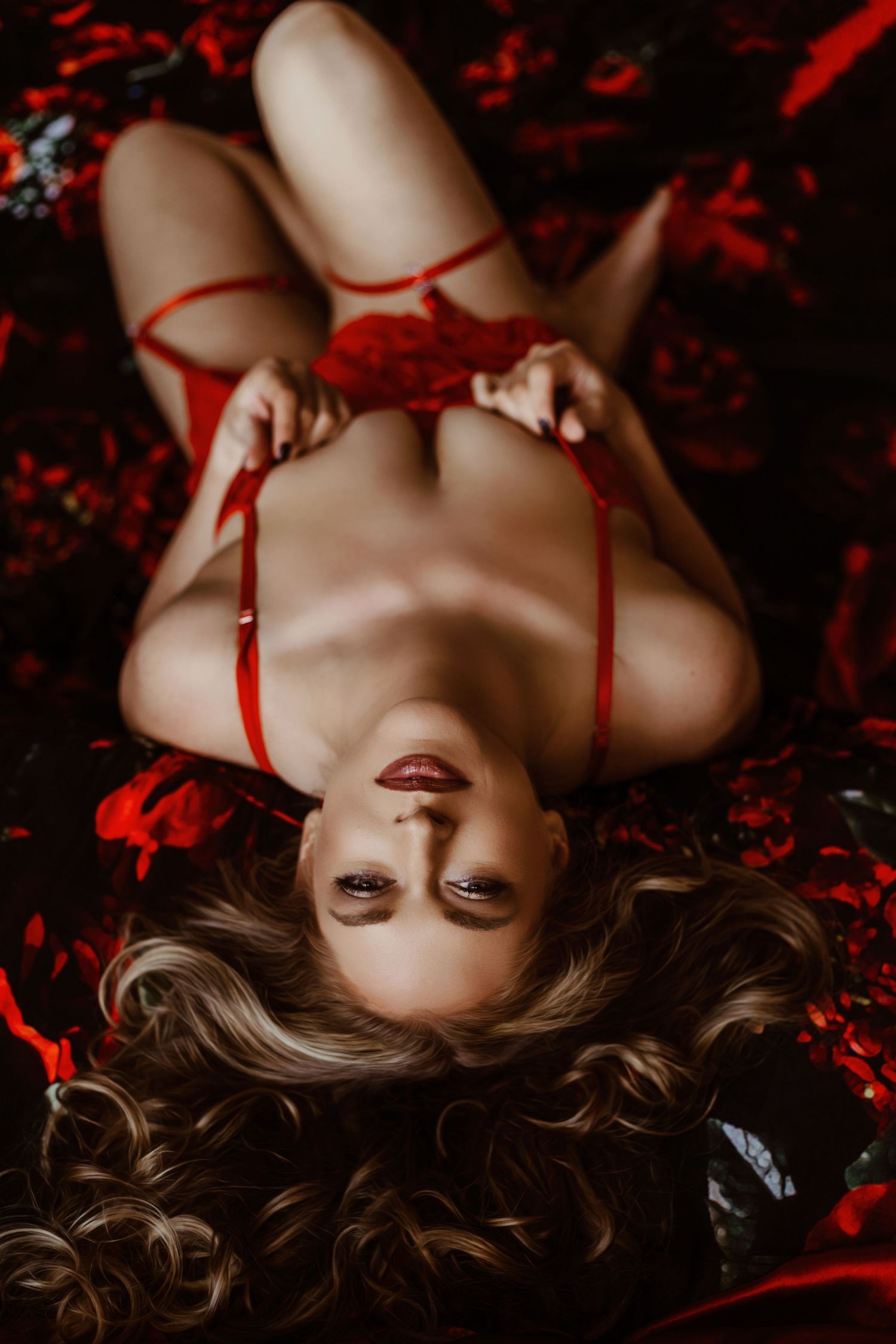 Dramatic overhead portrait with red styling elements against dark backdrop.