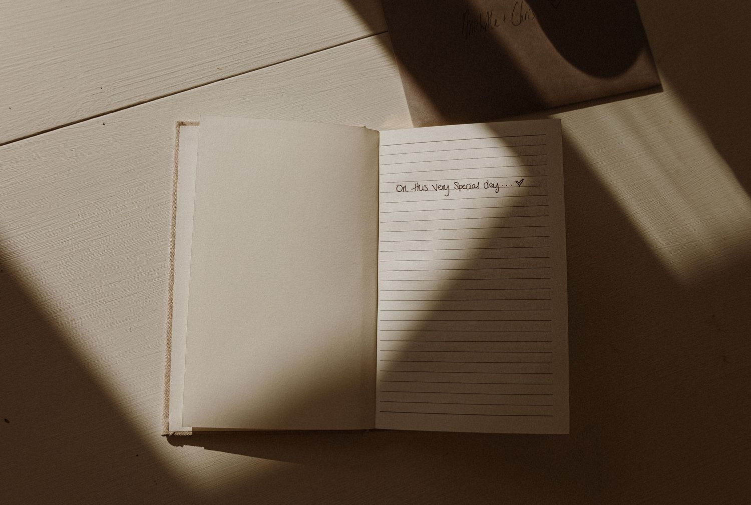 Open blank notebook with dramatic shadows cast across lined pages.