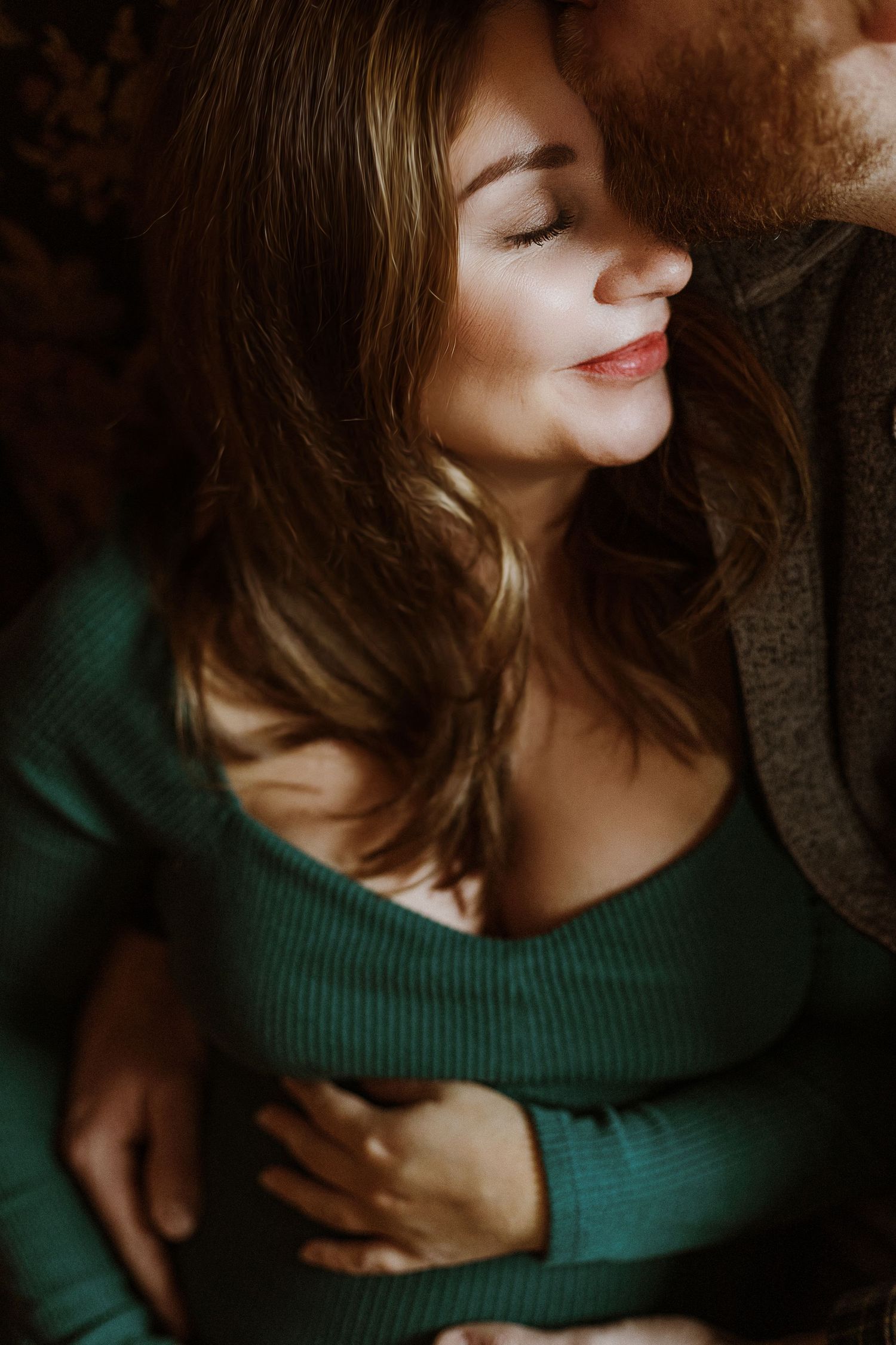 Intimate close-up portrait of a woman in a green sweater with soft natural lighting.
