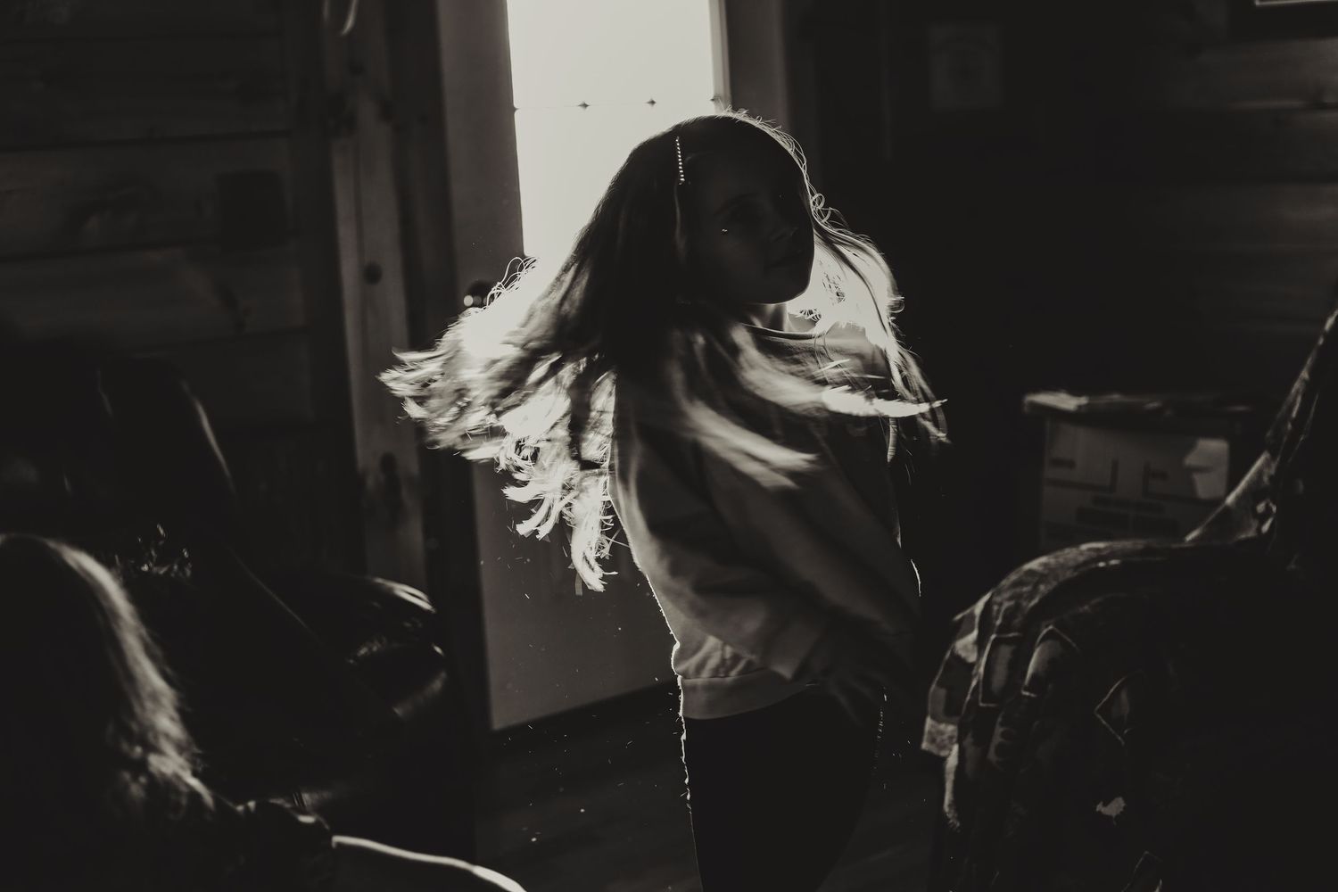 Black and white image of hair swishing in motion against window light.
