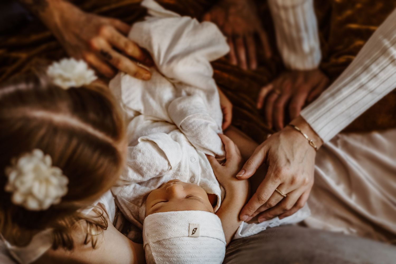 Newborn baby receiving a gentle massage with coconut oil during a traditional postpartum healing ritual.