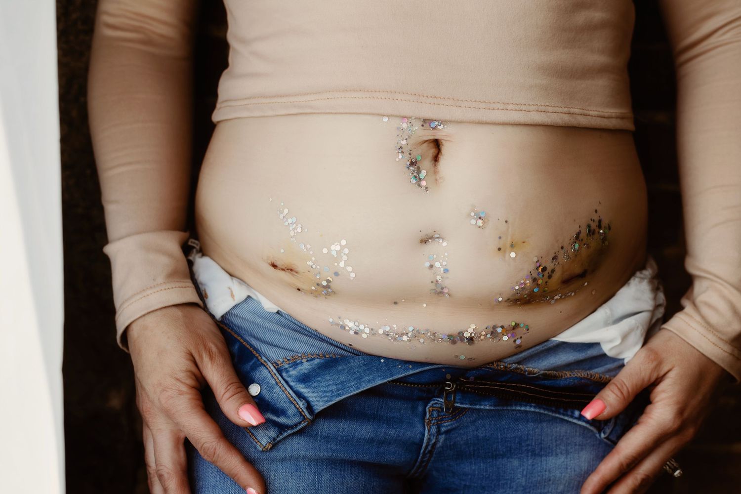 Close-up of pregnant belly with gold temporary tattoo decorations.