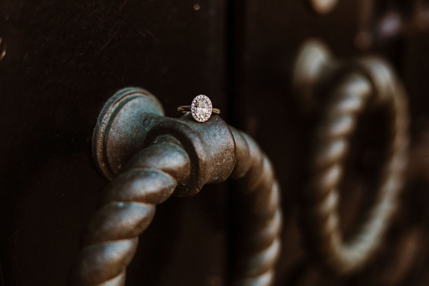 Diamond engagement ring placed on an ornate metal door handle.