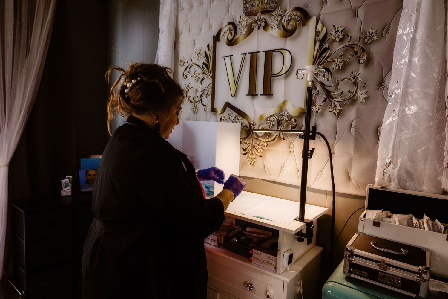 A silhouette works at a desk with ornate VIP signage and lighting equipment.