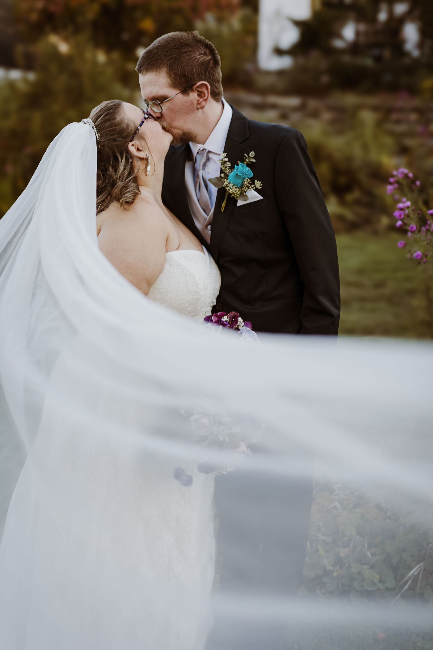 Romantic wedding portrait with flowing veil and intimate moment between newlyweds.