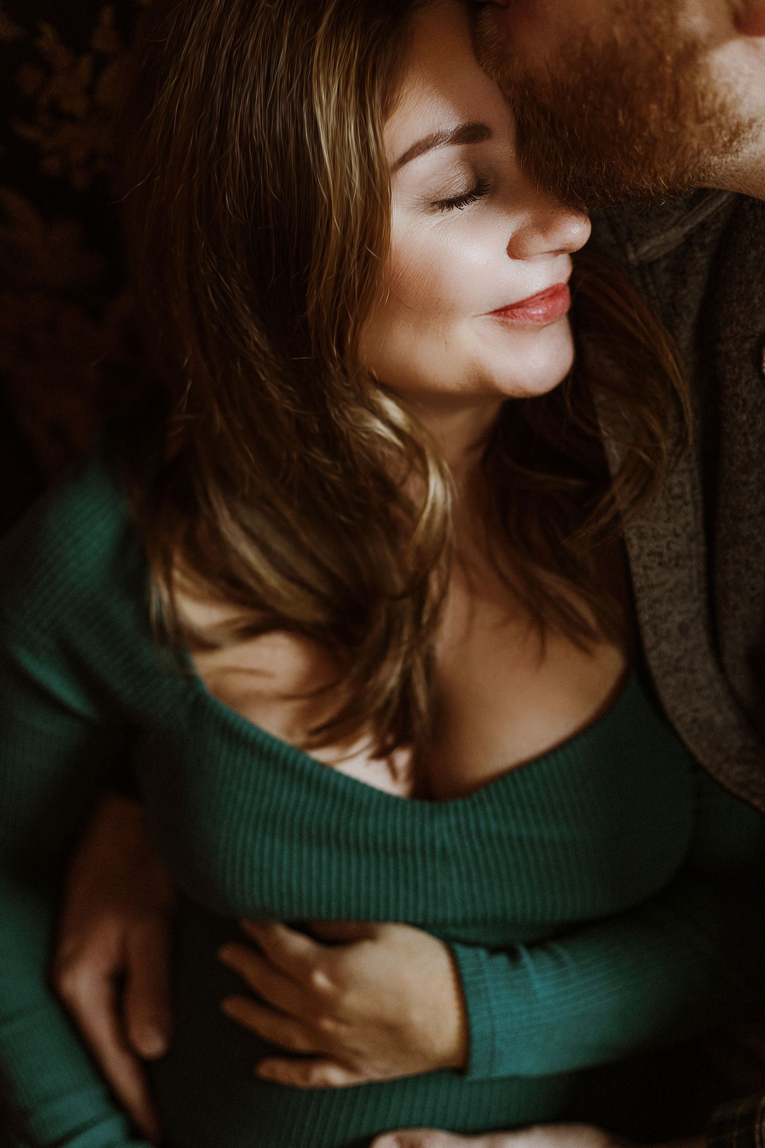 Intimate portrait in warm lighting with emerald green sweater and soft natural glow.