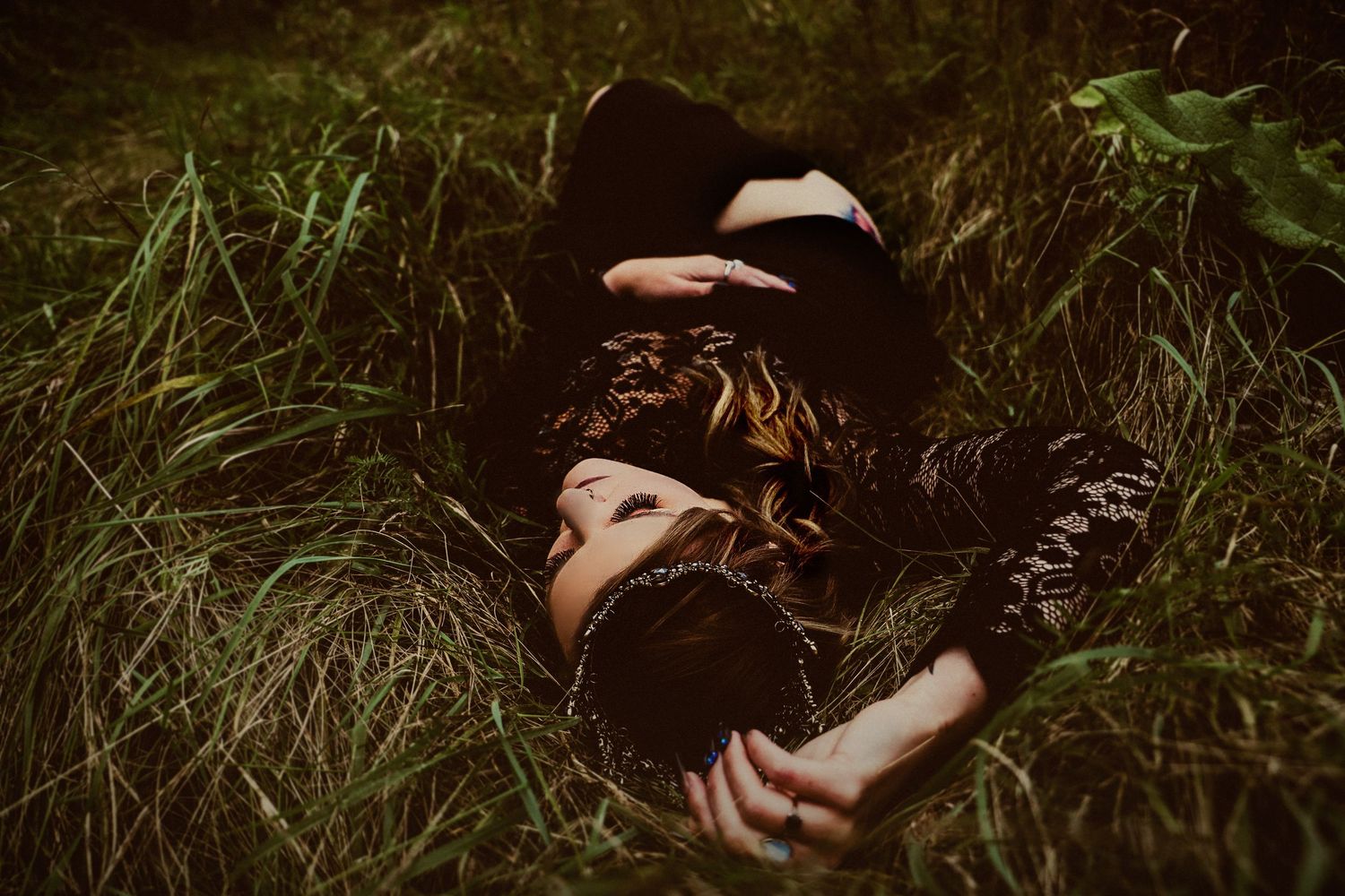 Moody outdoor portrait in tall grass with dark romantic styling.