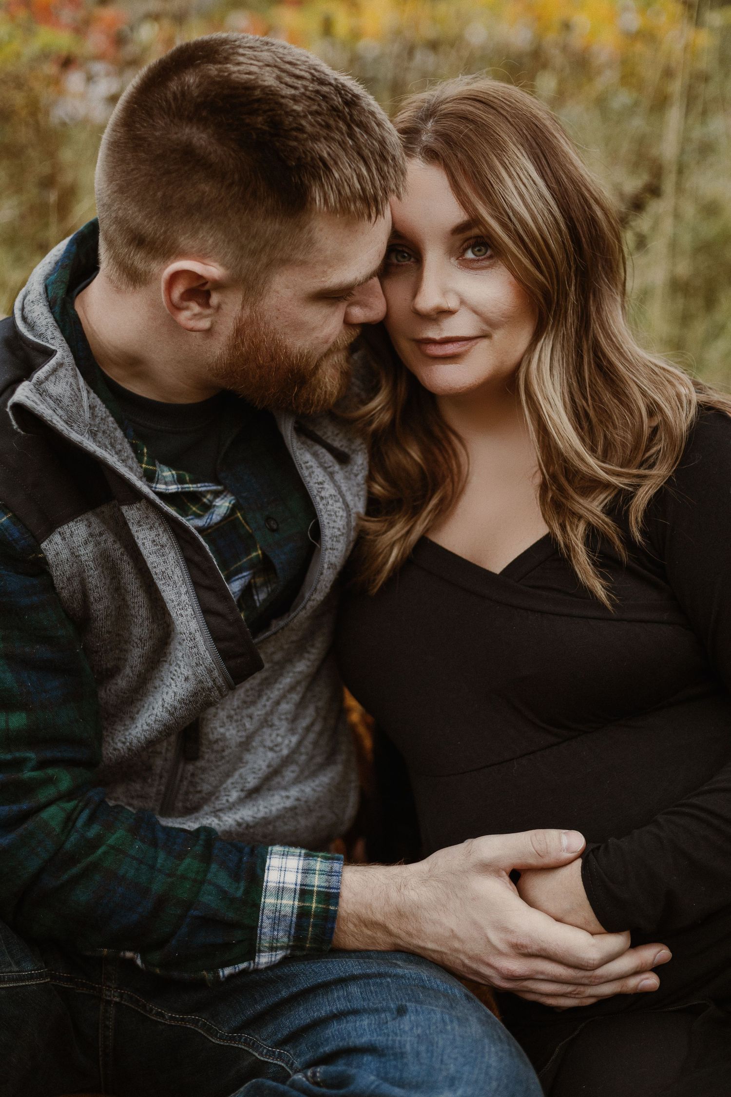 Intimate autumn outdoor portrait of an expectant couple in casual attire.