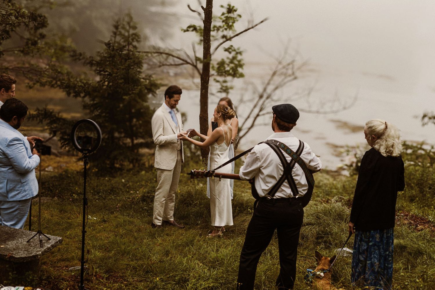 Intimate outdoor wedding ceremony in misty forest setting.