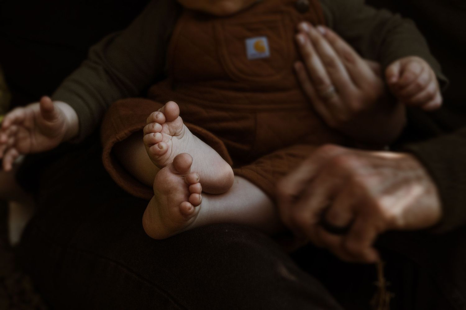 Close-up photo of tiny baby feet and hands against dark background.