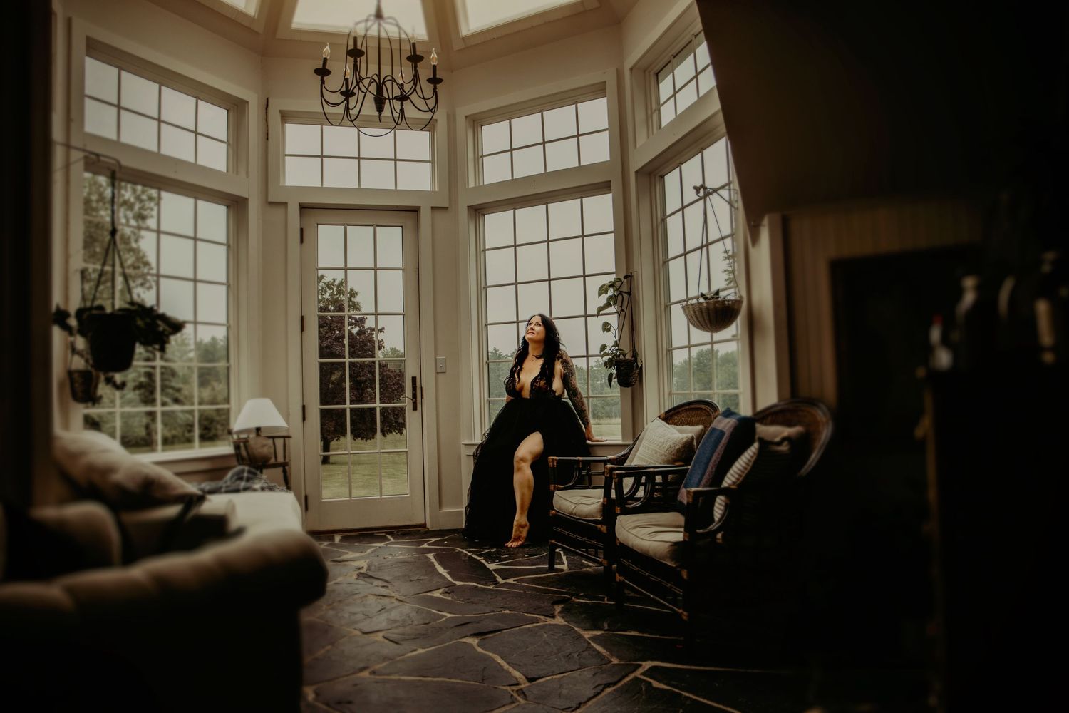 Elegant sunlit room with large bay windows and figure seated in vintage chair.
