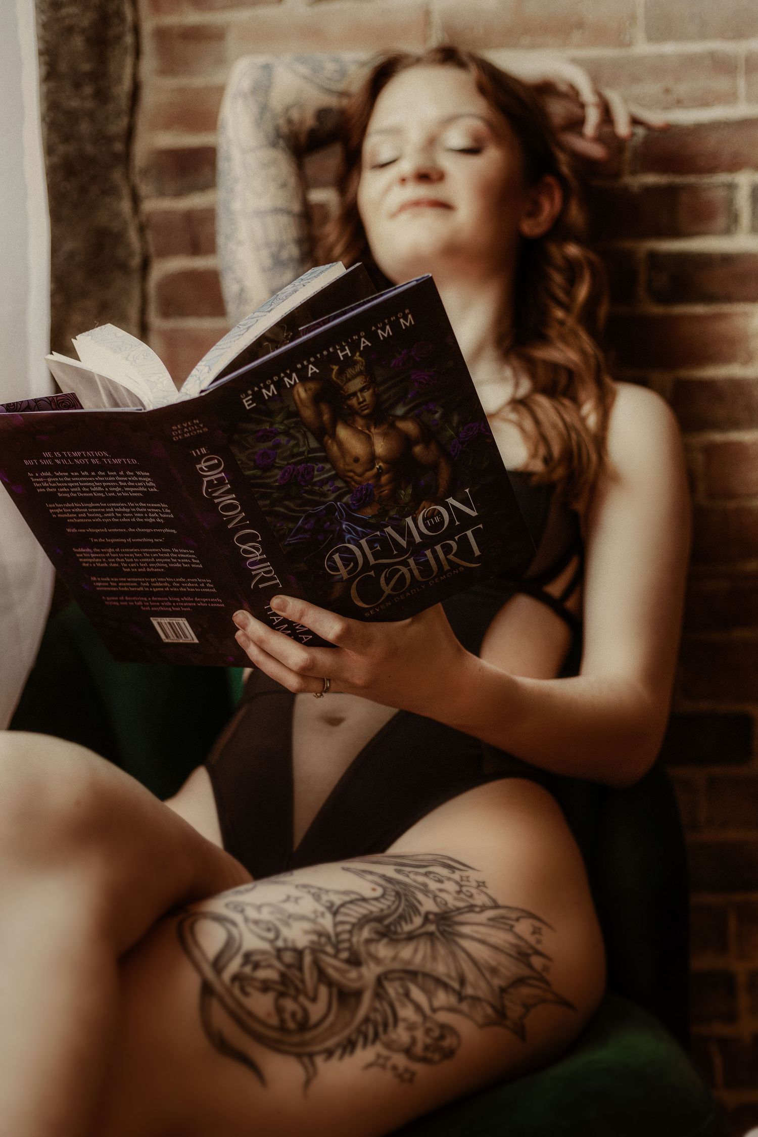 Reading a book in cozy corner with exposed brick wall and natural lighting.