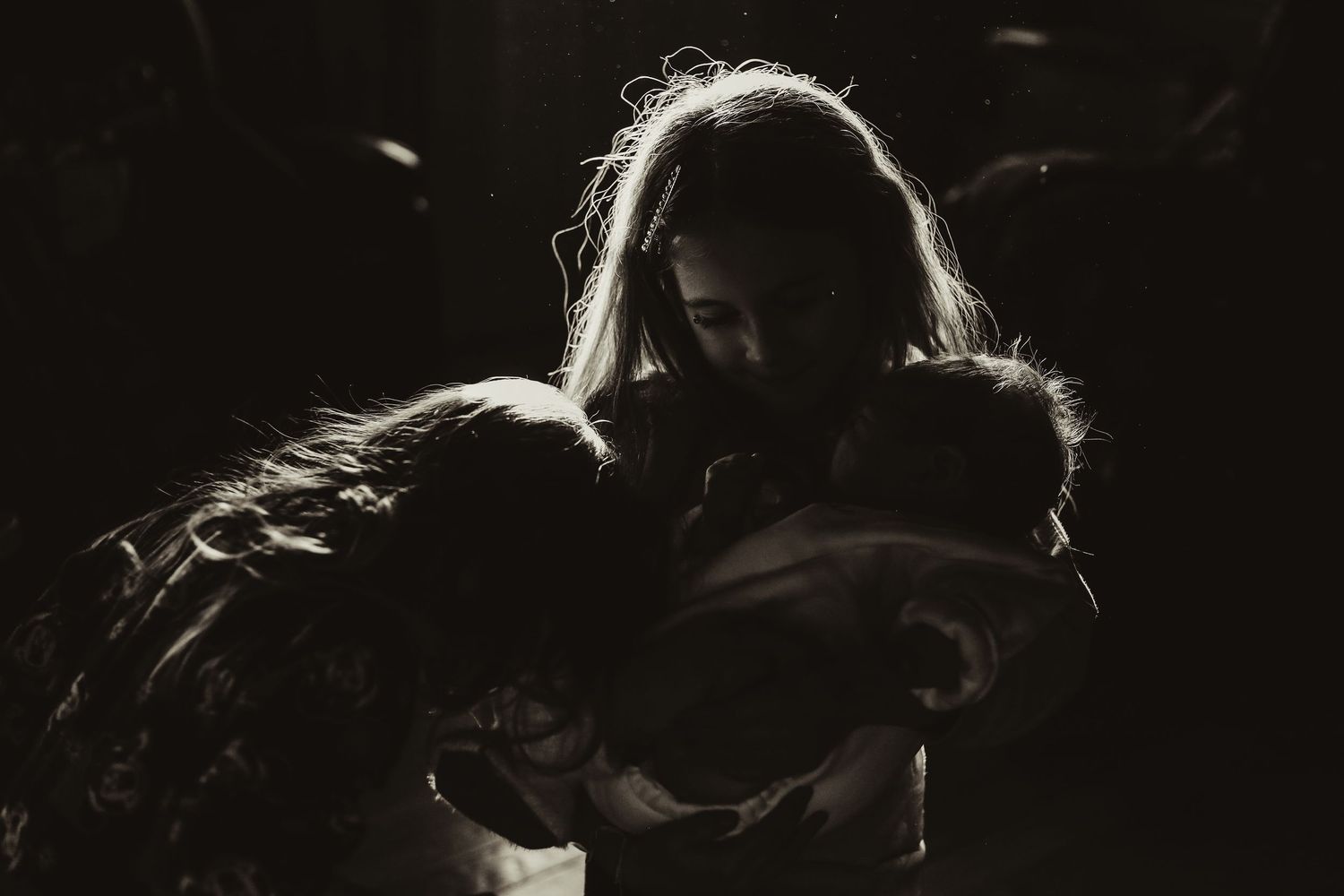 A dramatic black and white silhouette photo shows two figures in an intimate embrace against a dark background.