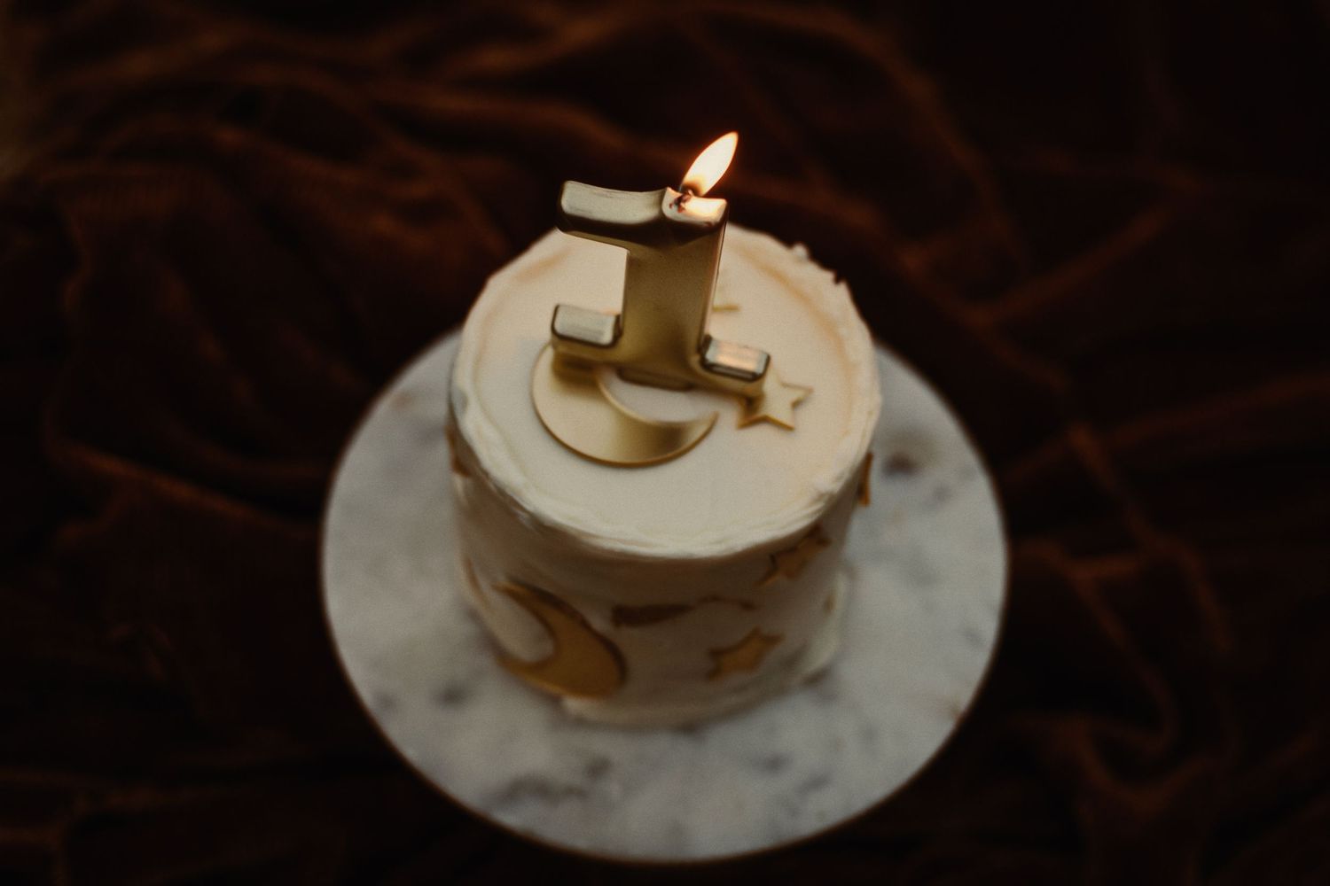 Small white birthday cake with number decoration on marble plate.