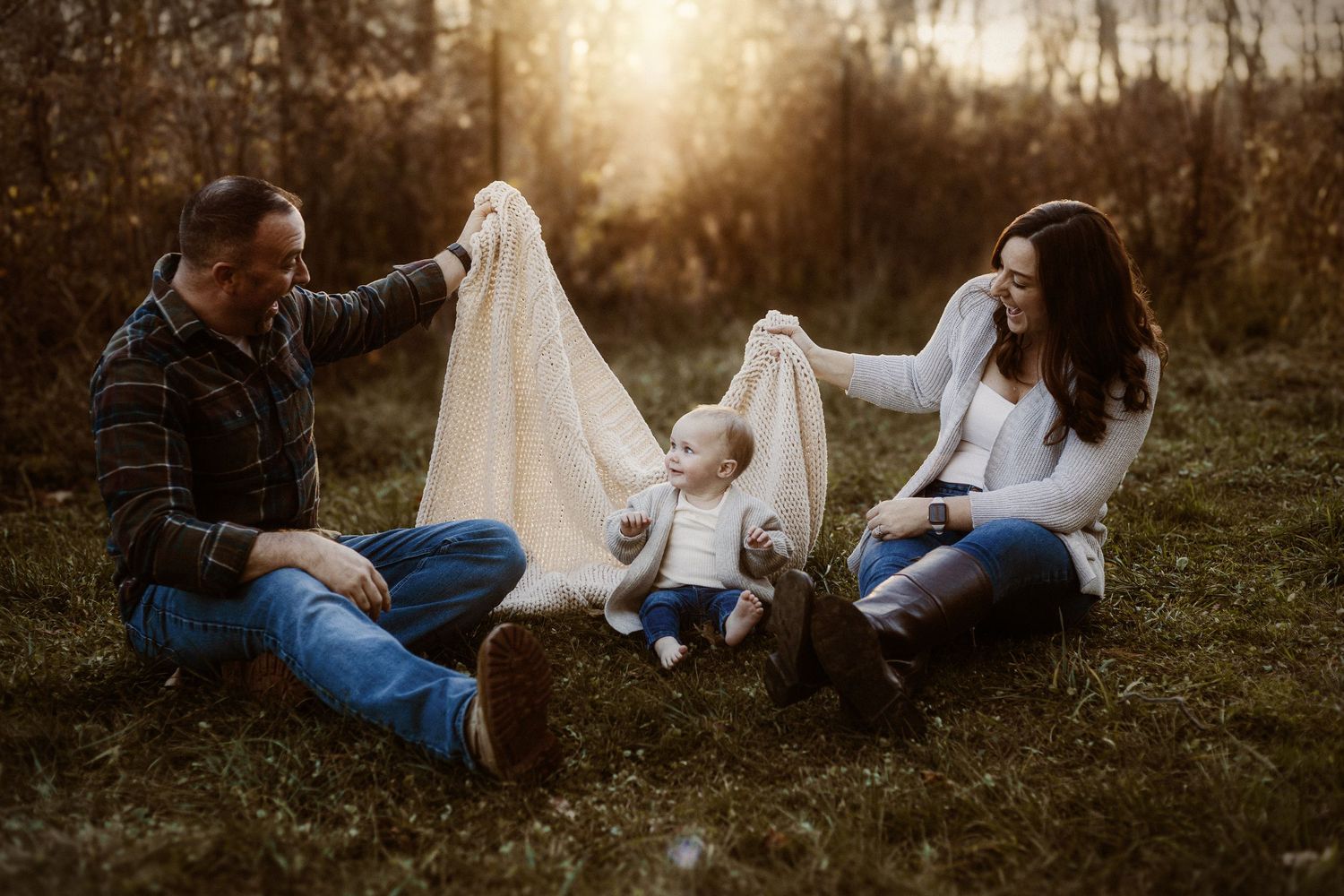 A family plays with ghost costumes in a sunset-lit field during autumn.